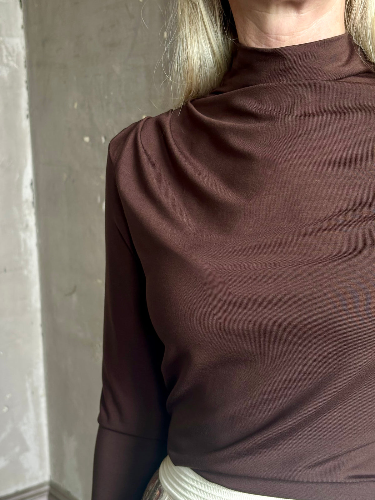Mature woman wearing Veronica Beard's Mylie Top in Espresso brown lightweight lyocell with asymmetrical shoulder draping and side ruching