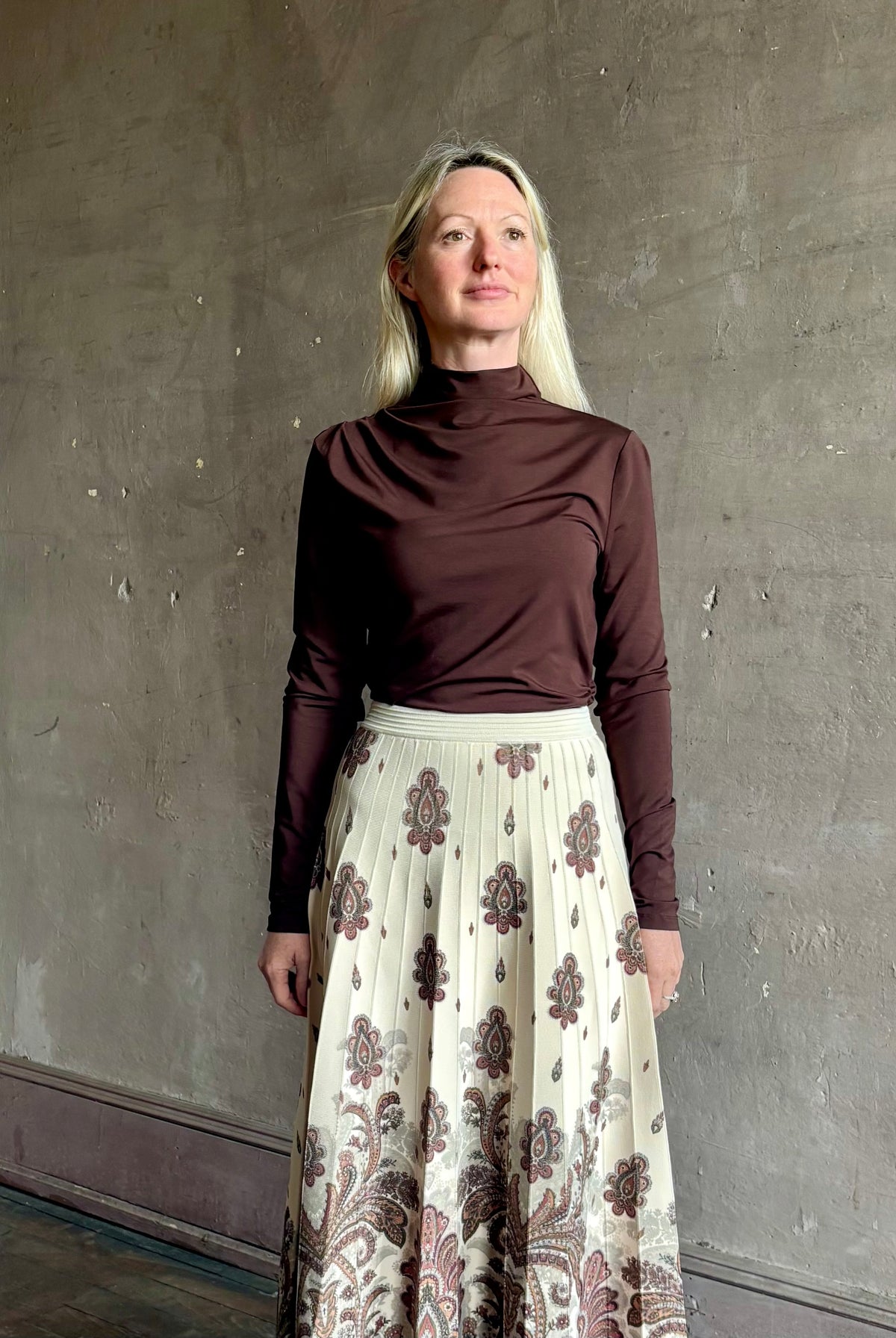 Mature woman wearing Veronica Beard's Mylie Top in Espresso brown lightweight lyocell with asymmetrical shoulder draping and side ruching