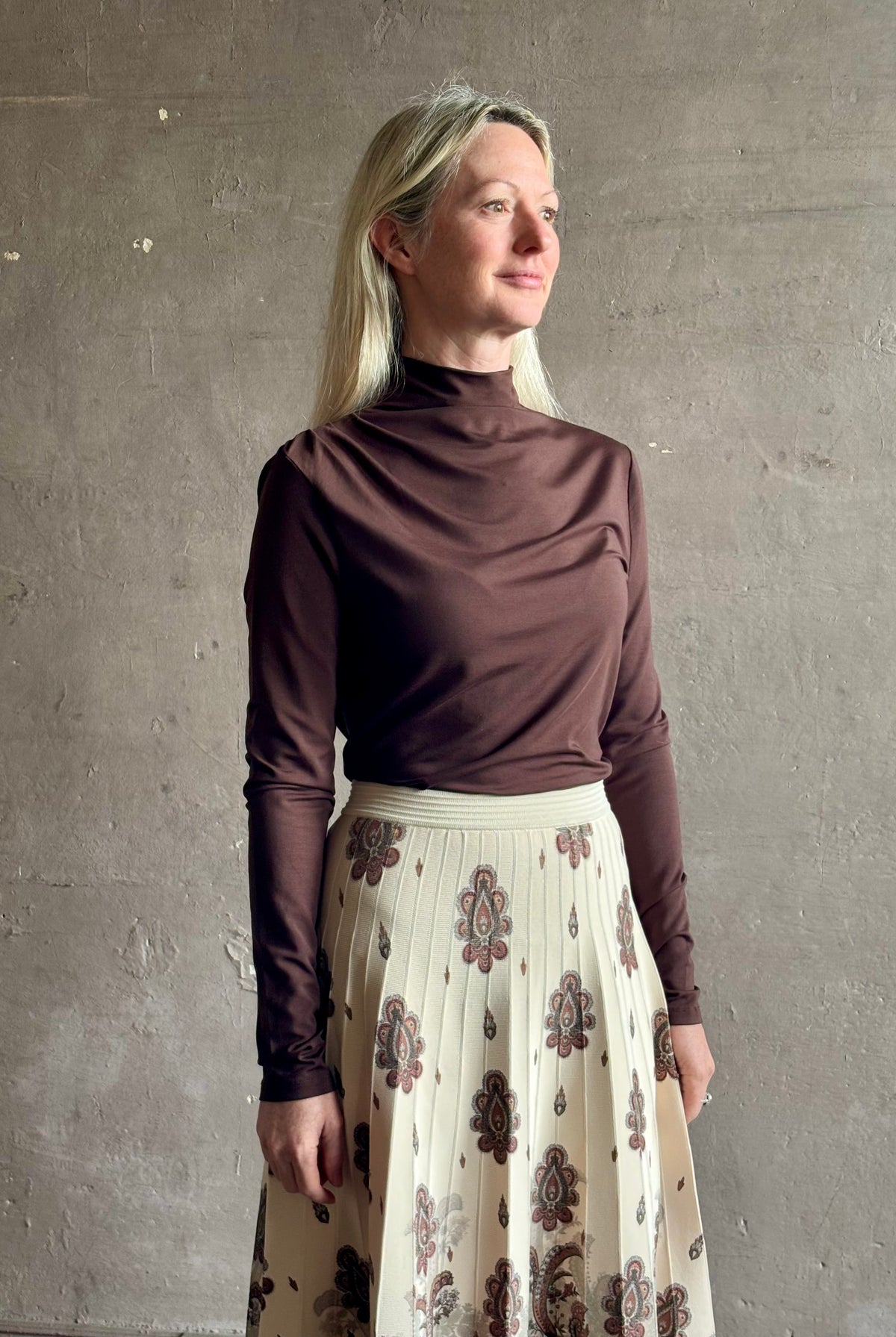 Mature woman wearing Veronica Beard's Mylie Top in Espresso brown lightweight lyocell with asymmetrical shoulder draping and side ruching
