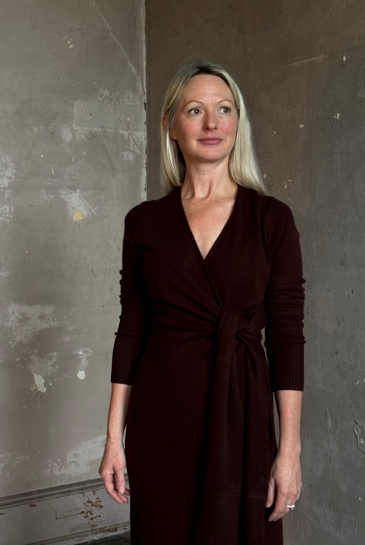 Mature woman wearing Veronica Beard's Salomez Knit Dress in chocolate brown wrap maxi with a V-neckline and side vent