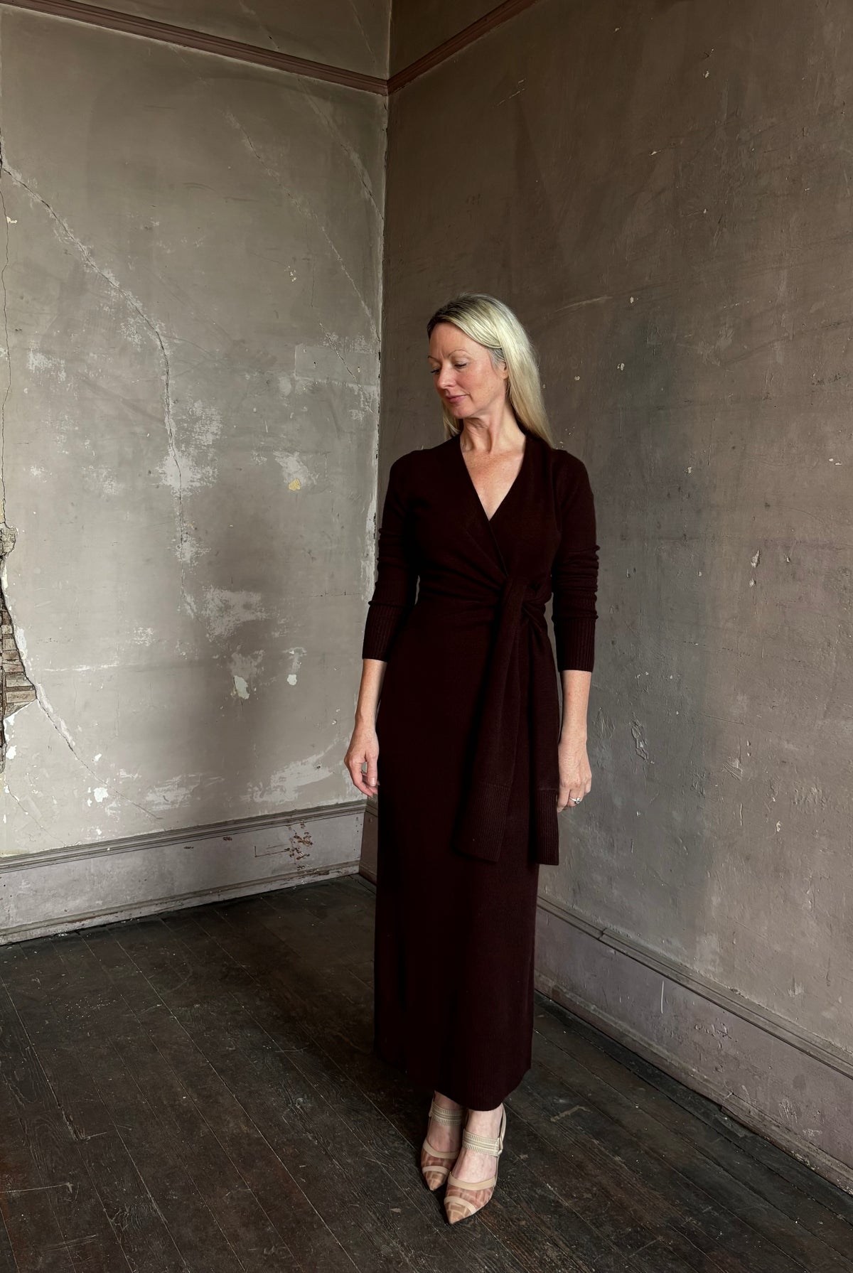 Mature woman wearing Veronica Beard's Salomez Knit Dress in chocolate brown wrap maxi with a V-neckline and side vent