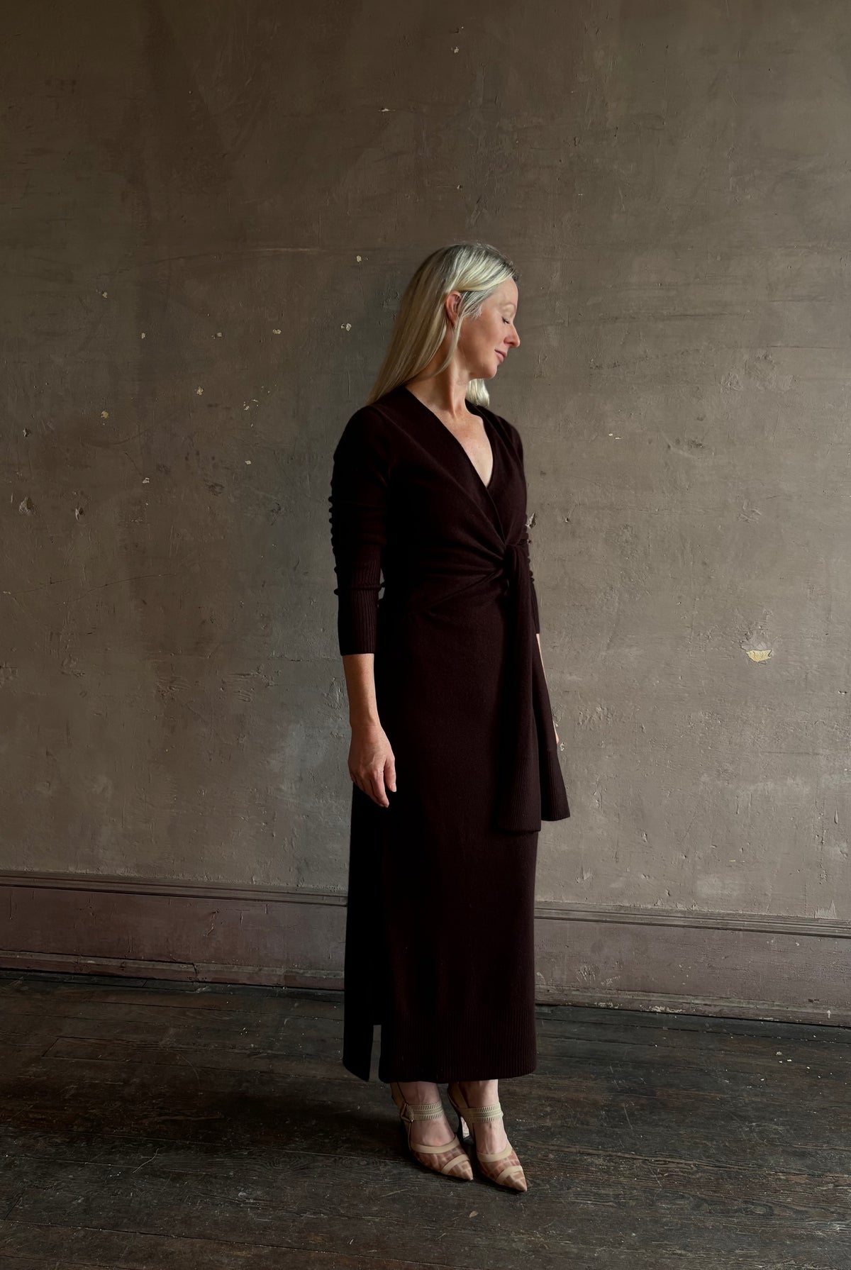 Mature woman wearing Veronica Beard's Salomez Knit Dress in chocolate brown wrap maxi with a V-neckline and side vent