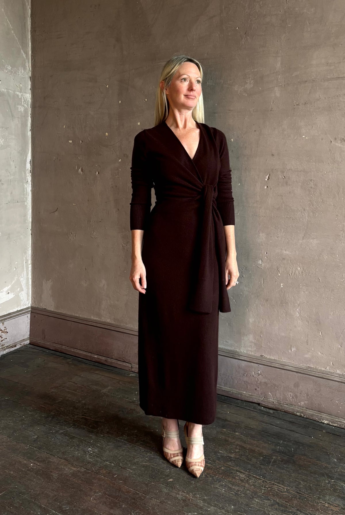 Mature woman wearing Veronica Beard's Salomez Knit Dress in chocolate brown wrap maxi with a V-neckline and side vent