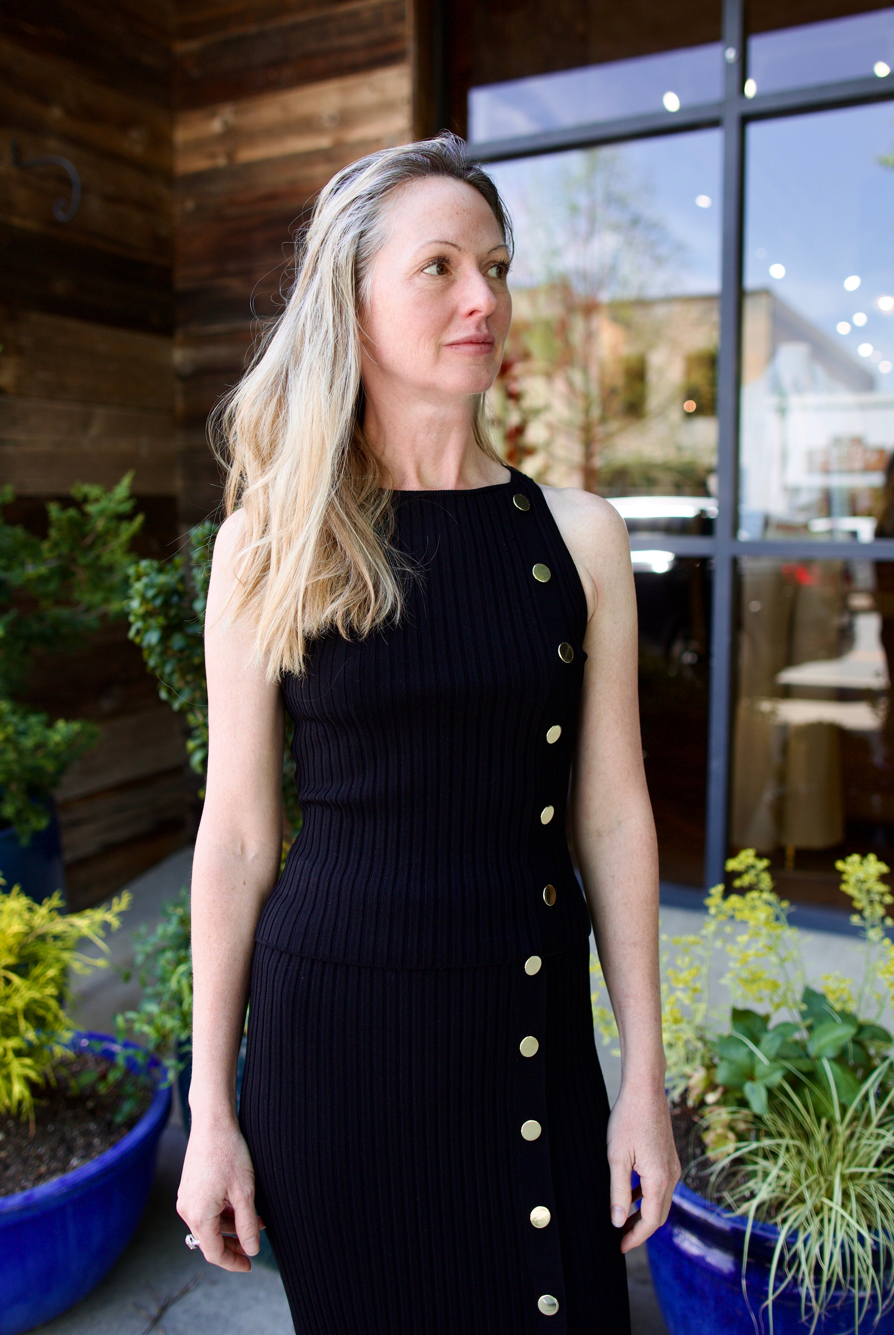 woman wearing Veronica Beard black knit Tanner Skirt with gold buttons leg vent comfy stretchy ribbed texture