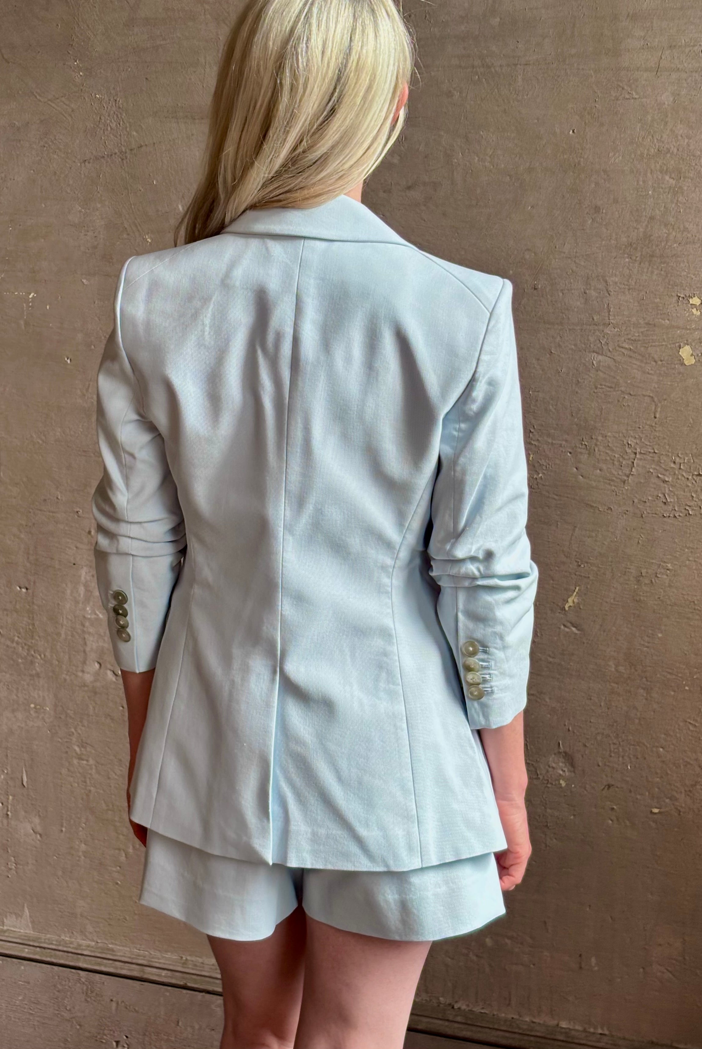 Mature woman wearing timeless Veronica Beard Tomi Dickey Jacket light blue ruched sleeves feminine tailoring