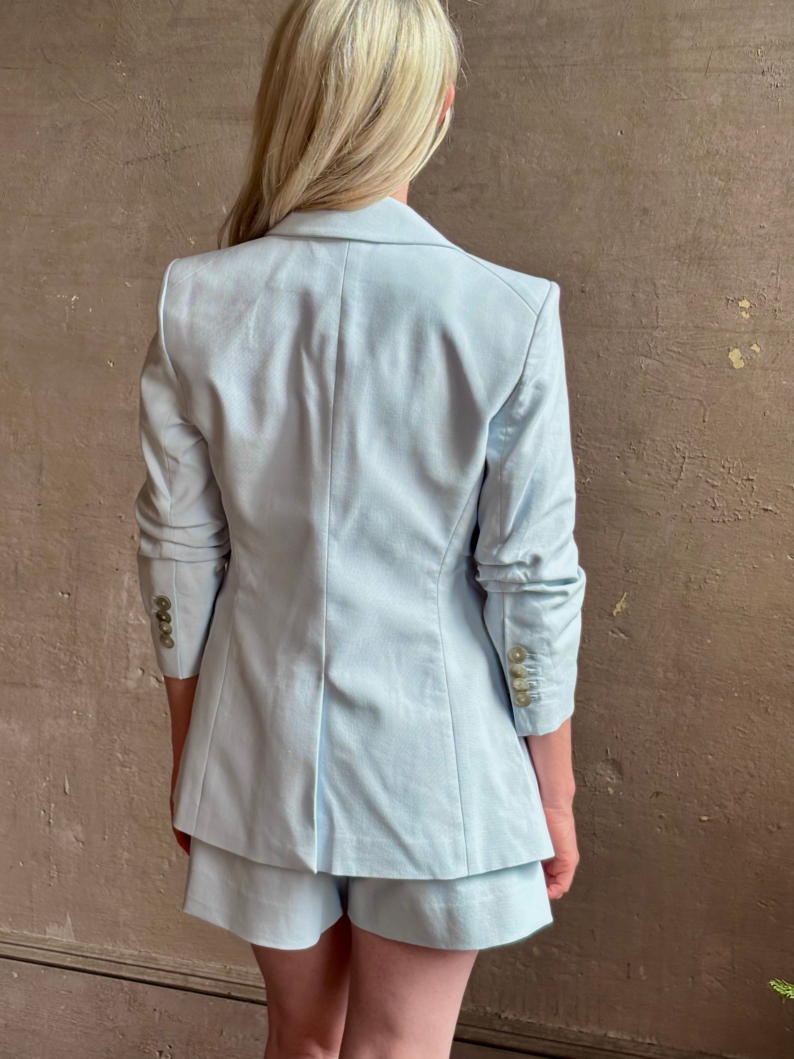 Mature woman wearing timeless Veronica Beard Tomi Dickey Jacket light blue ruched sleeves feminine tailoring
