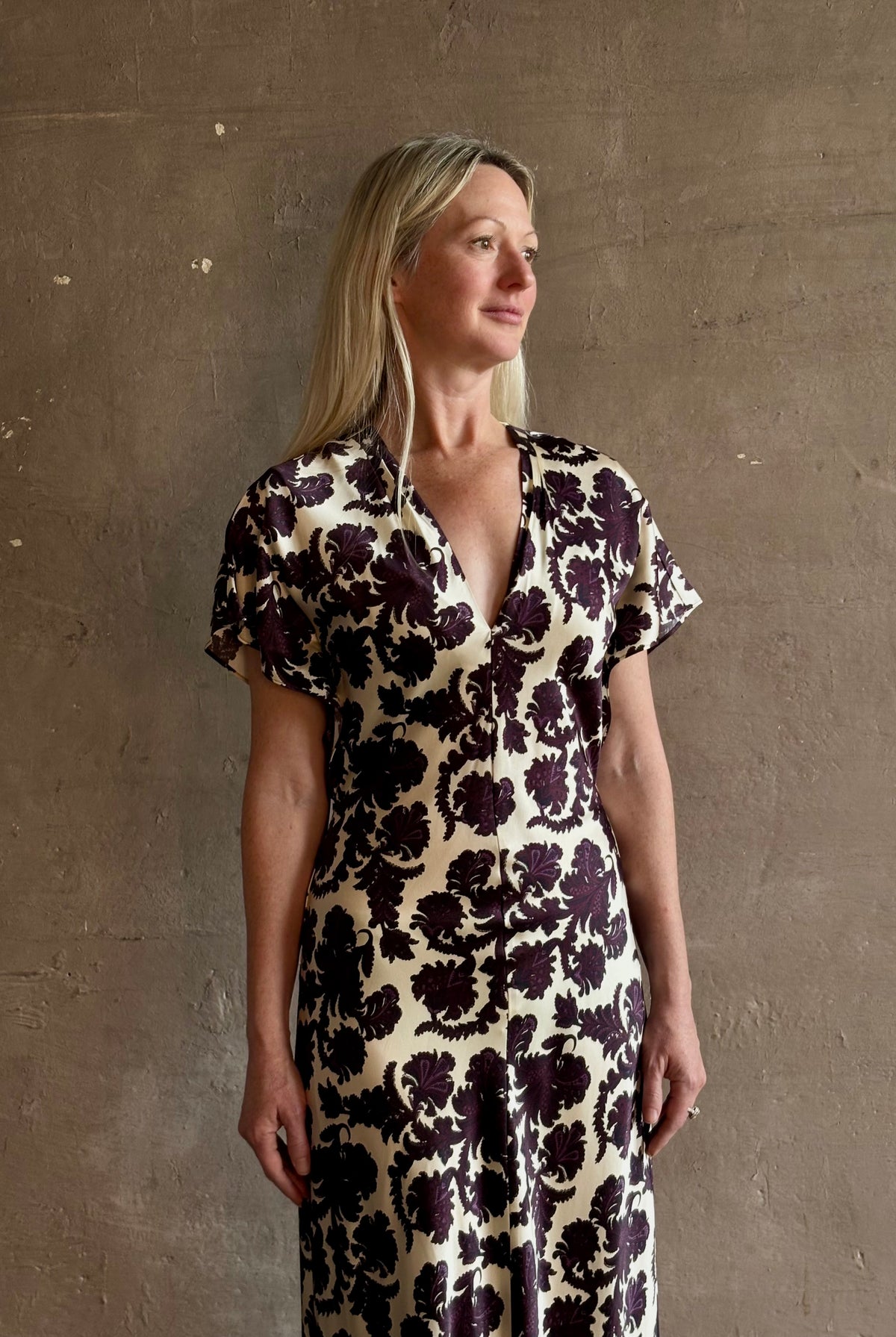 Mature woman wearing designer Veronica Beard V-Neck Redgrave Dress in Ecru Multi sheath maxi with a rich purple floral print Elongating, occasion-ready