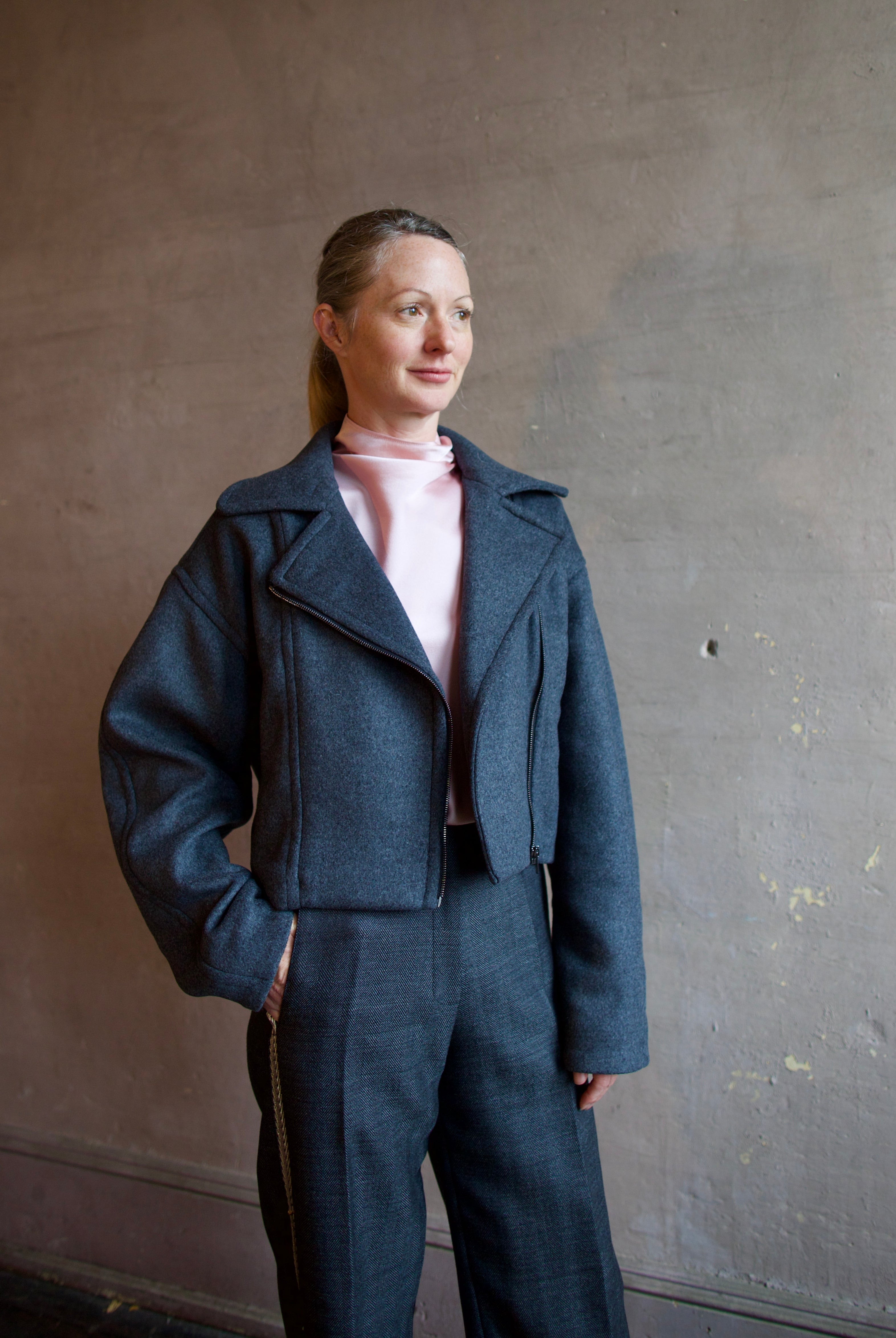 Image featuring a woman wearing the Bless jacket by Vanessa Bruno with an asymmetrical zipper, full sleeve and a slightly cropped fit in dark grey.