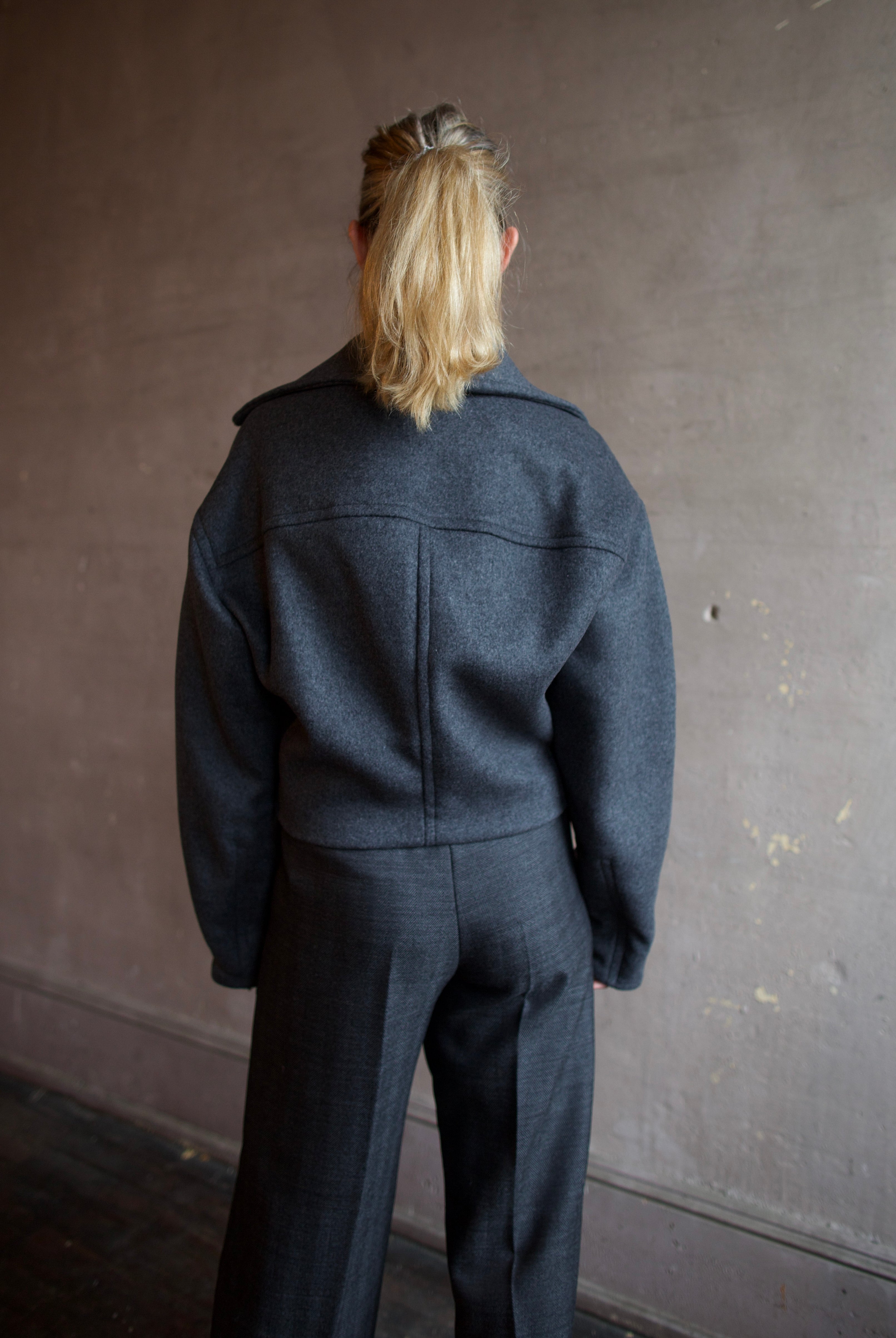 Image featuring a woman wearing the Bless jacket by Vanessa Bruno with an asymmetrical zipper, full sleeve and a slightly cropped fit in dark grey.