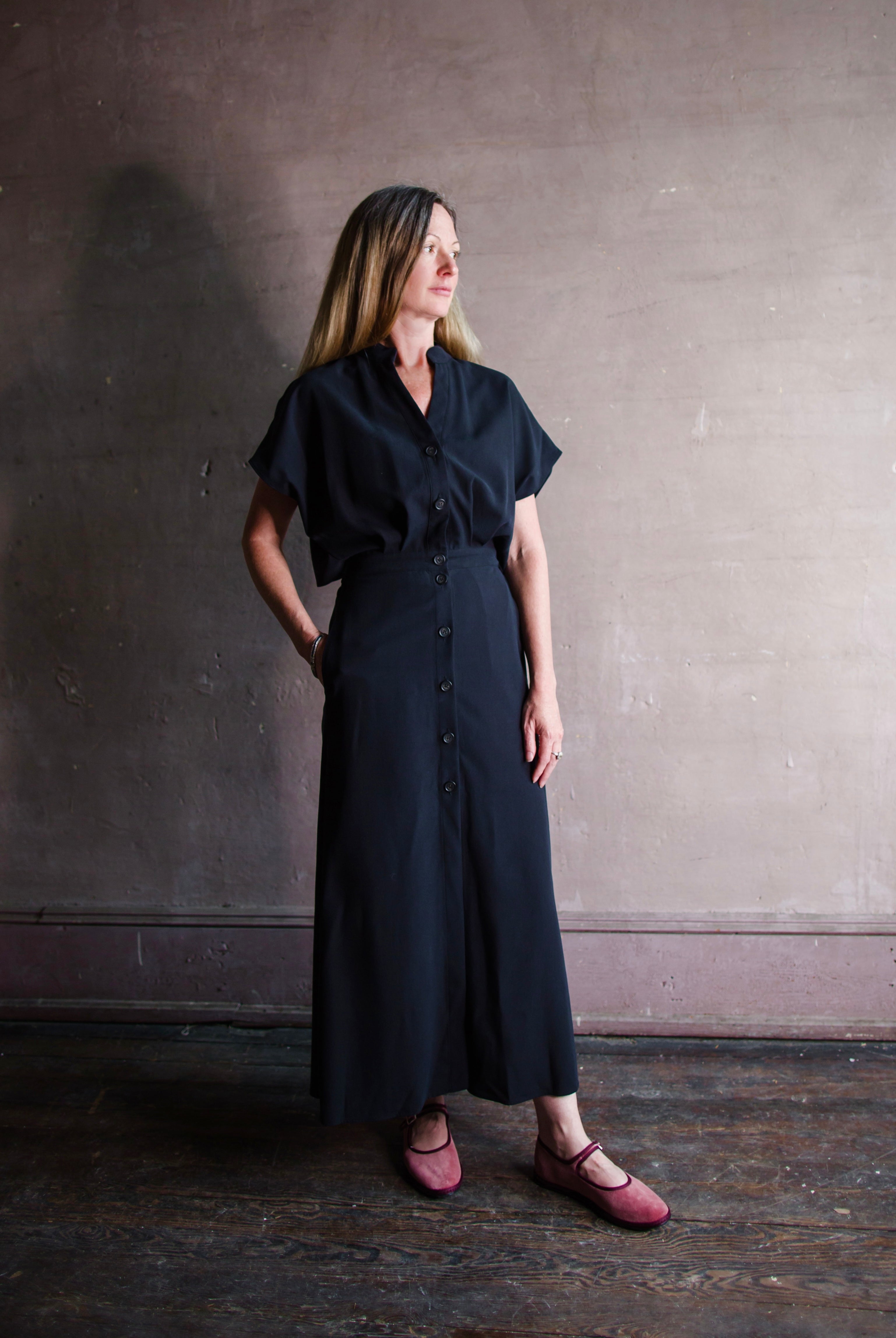 Image featuring a woman wearing the Cheryle dress by Vanessa Bruno in lyocell with a button front and tailored skirting with an open back in navy blue colorway.
