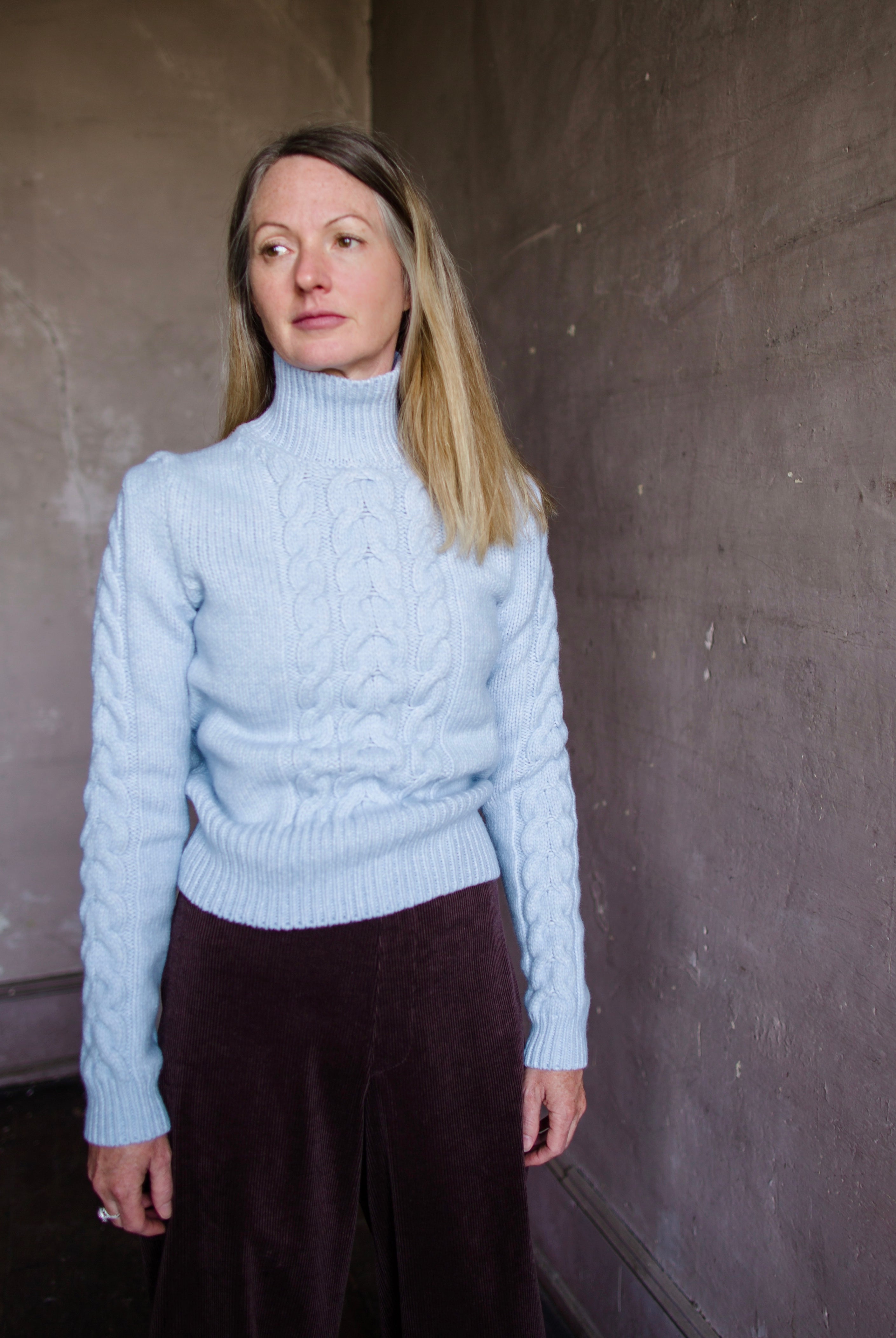 Woman wearing Vanessa Bruno dabatha cable knit turtleneck sweater in shade azure merino wool blend