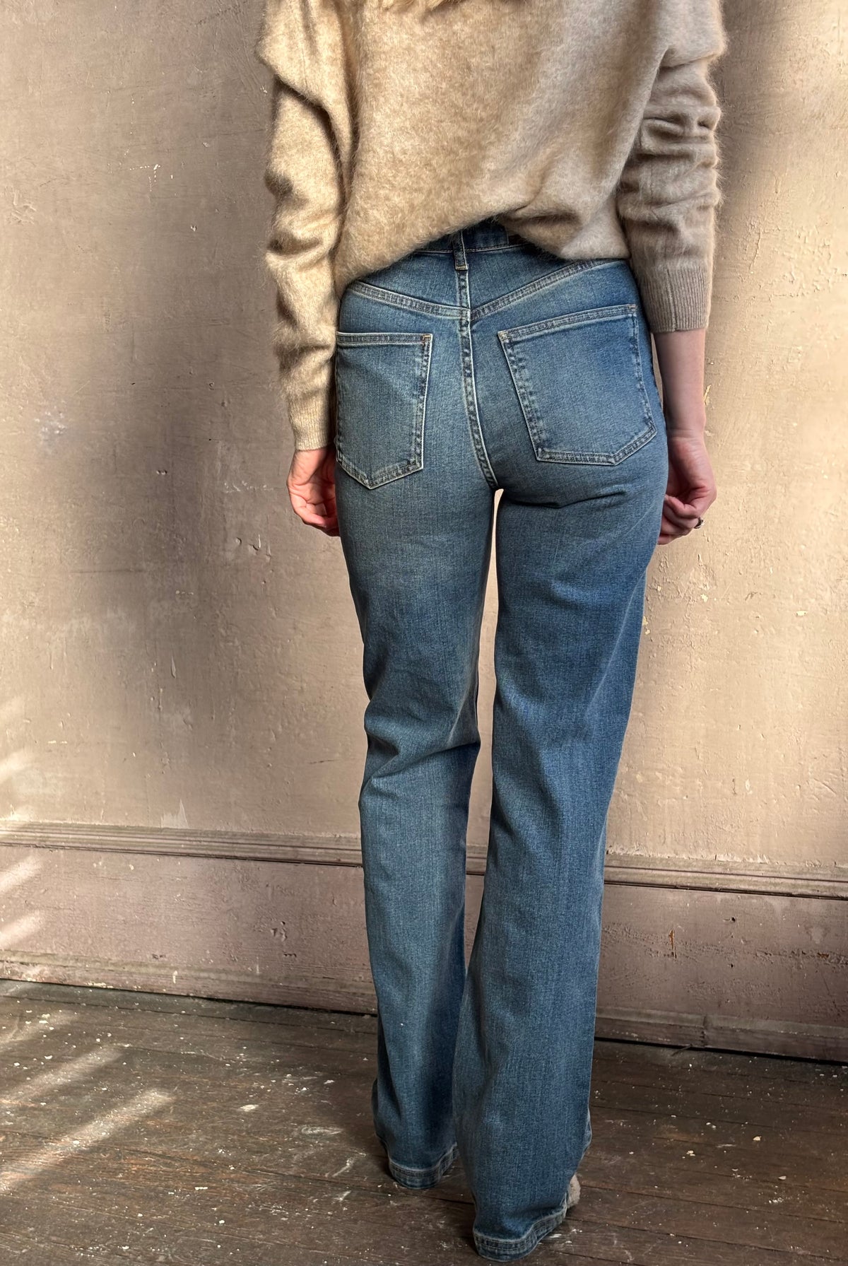 Close up back image of woman wearing Vanessa Bruno Benito high rise jeans with straight leg full length medium wash V detail and two patch pockets