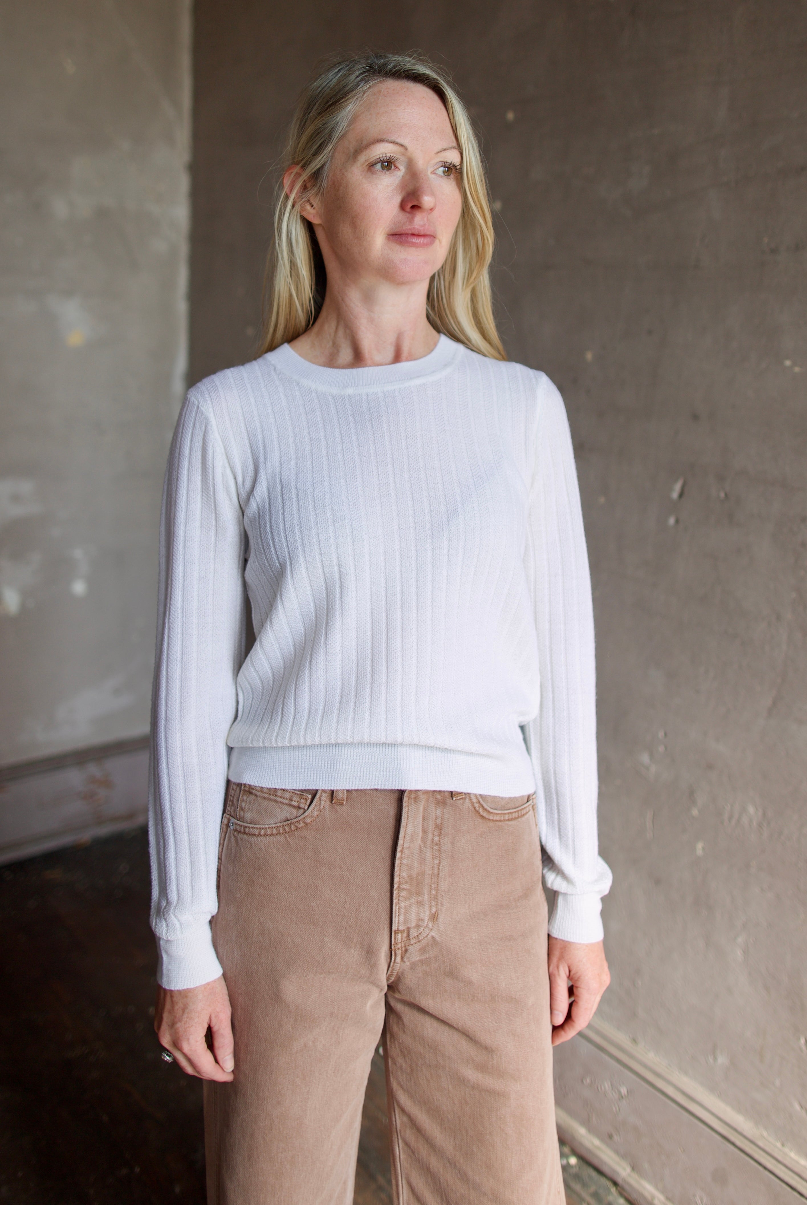 Model wearing Veronica Beard premium wool cheval pullover in ivory with lightweight wide ribbed texture, long sleeves, and crew neck