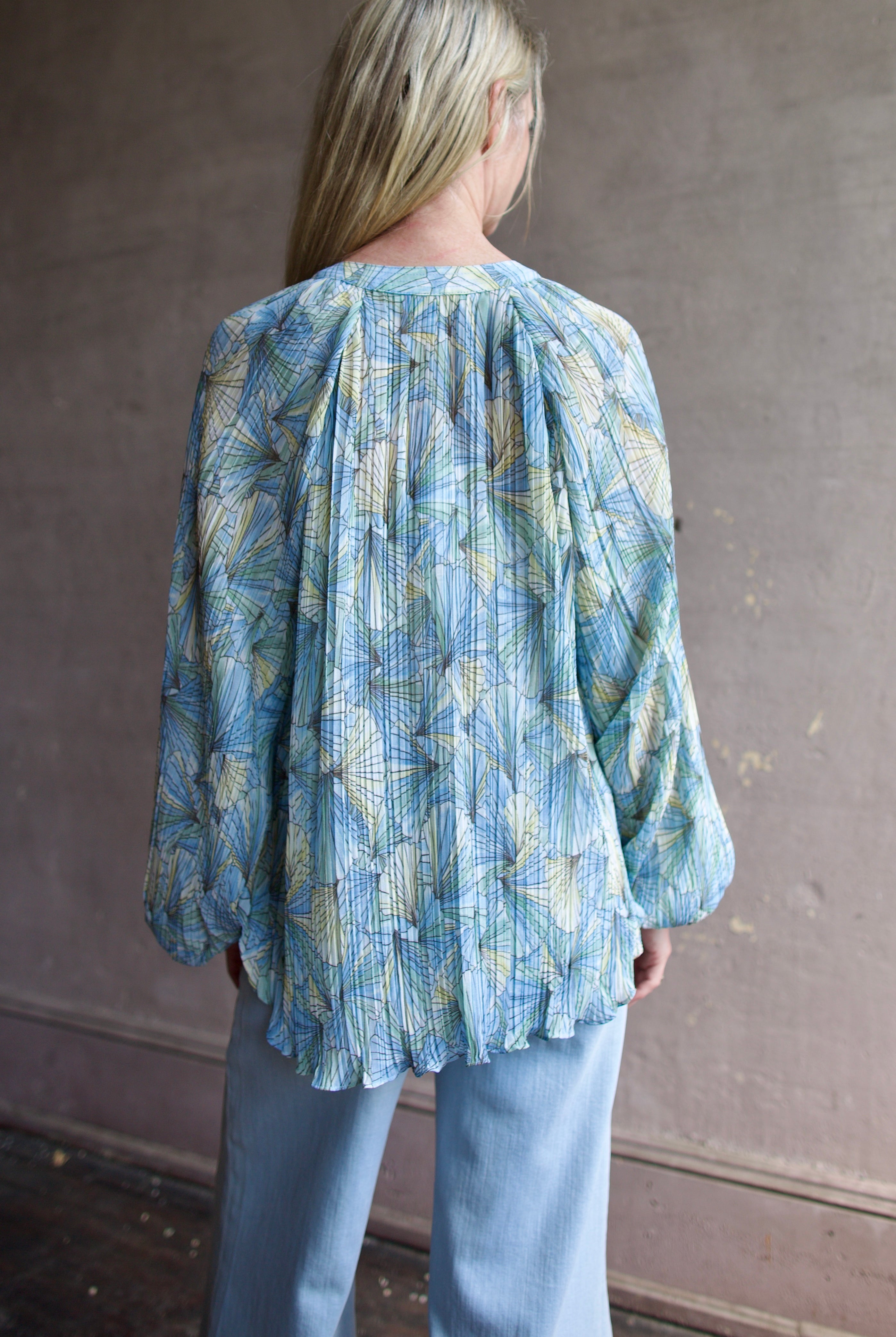 Mature womanl wearing designer Veronica Beard Fennel Pleated Blouse with long sleeve in flowy effortless Bohemian style and wrinkle free perfect to pack for vacation
