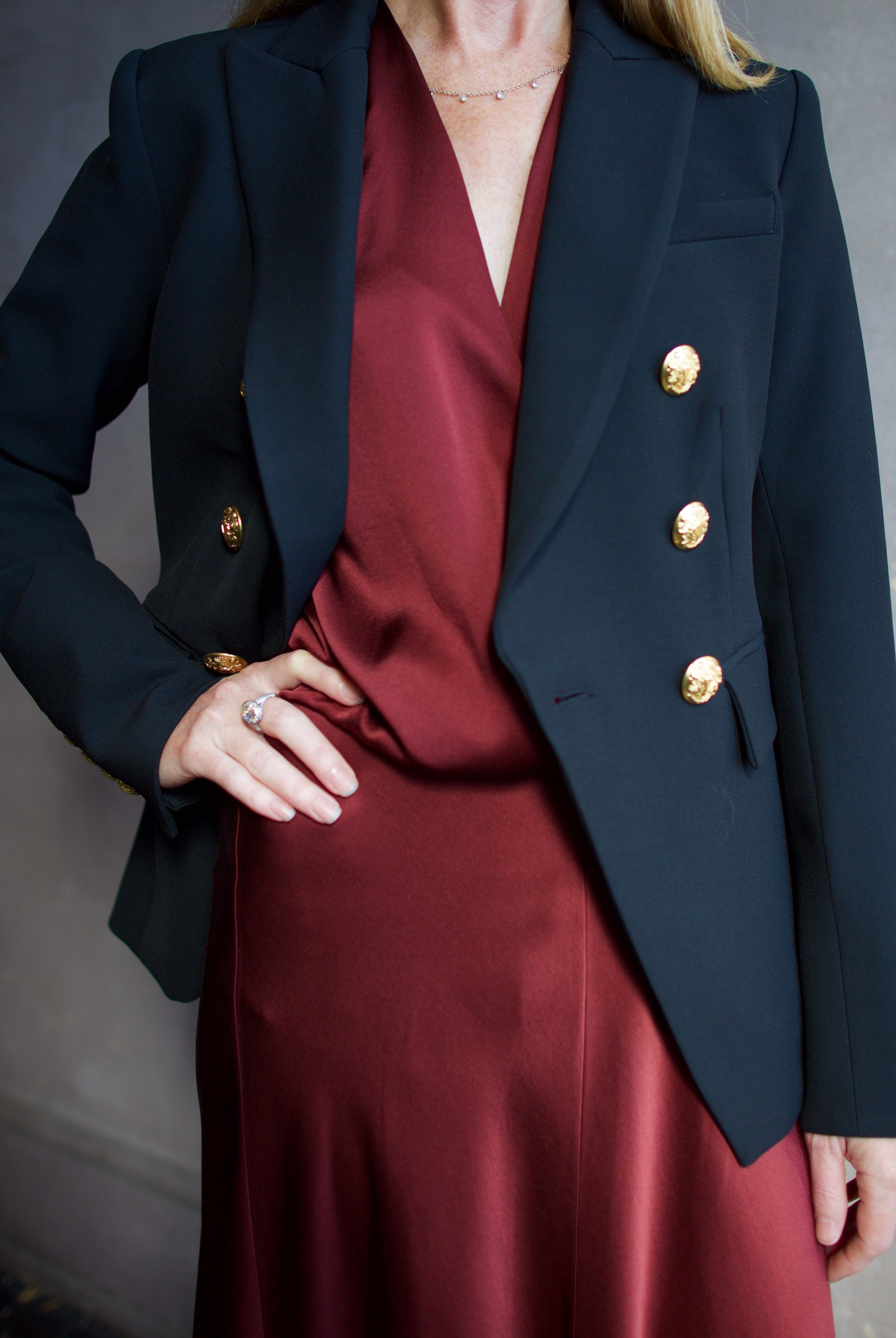Image featuring a woman wearing the Miller Dickey Jacket by Veronica Beard with a double breasted closure and tailored fit in black with gold color buttons.