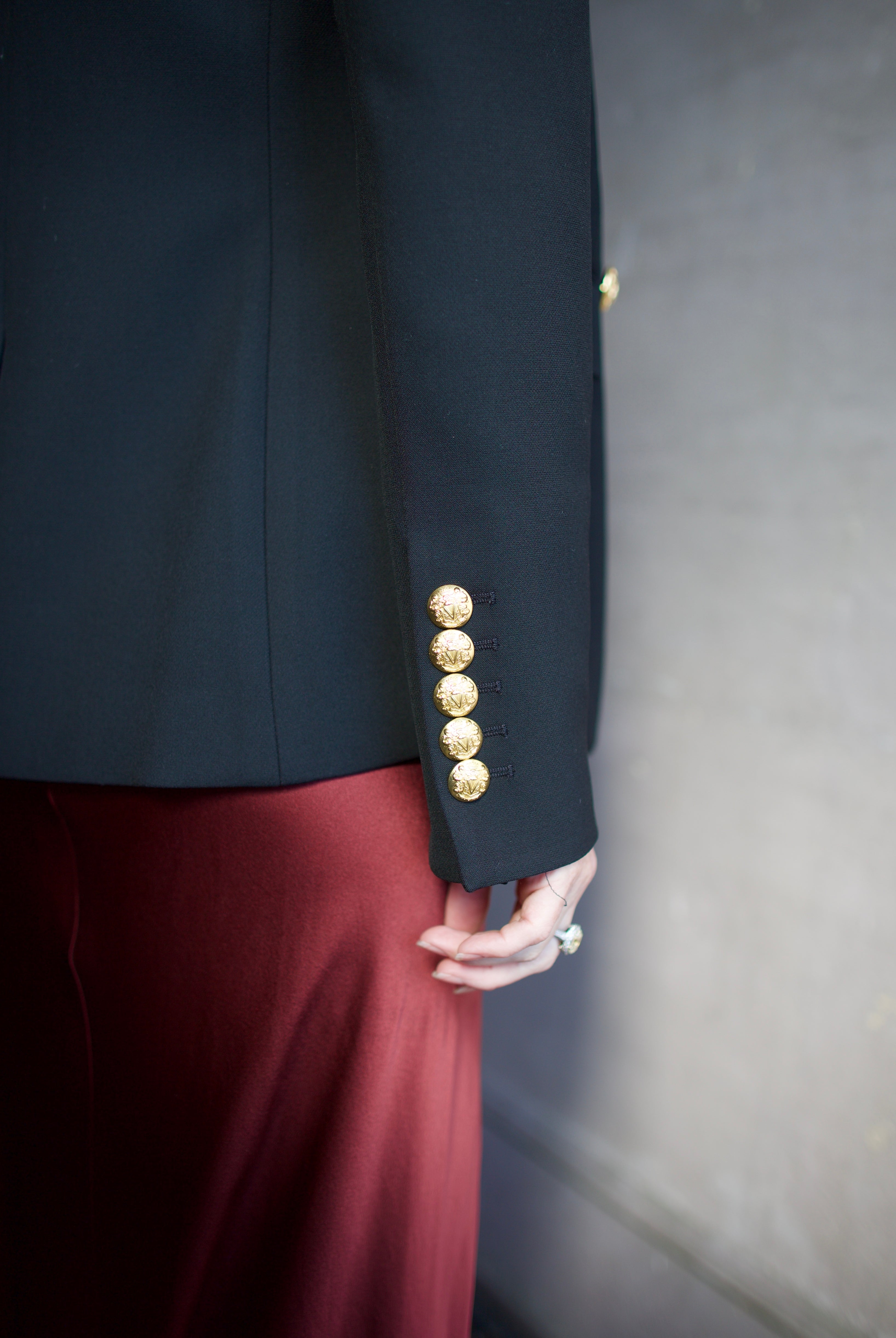 Image featuring a woman wearing the Miller Dickey Jacket by Veronica Beard with a double breasted closure and tailored fit in black with gold color buttons.