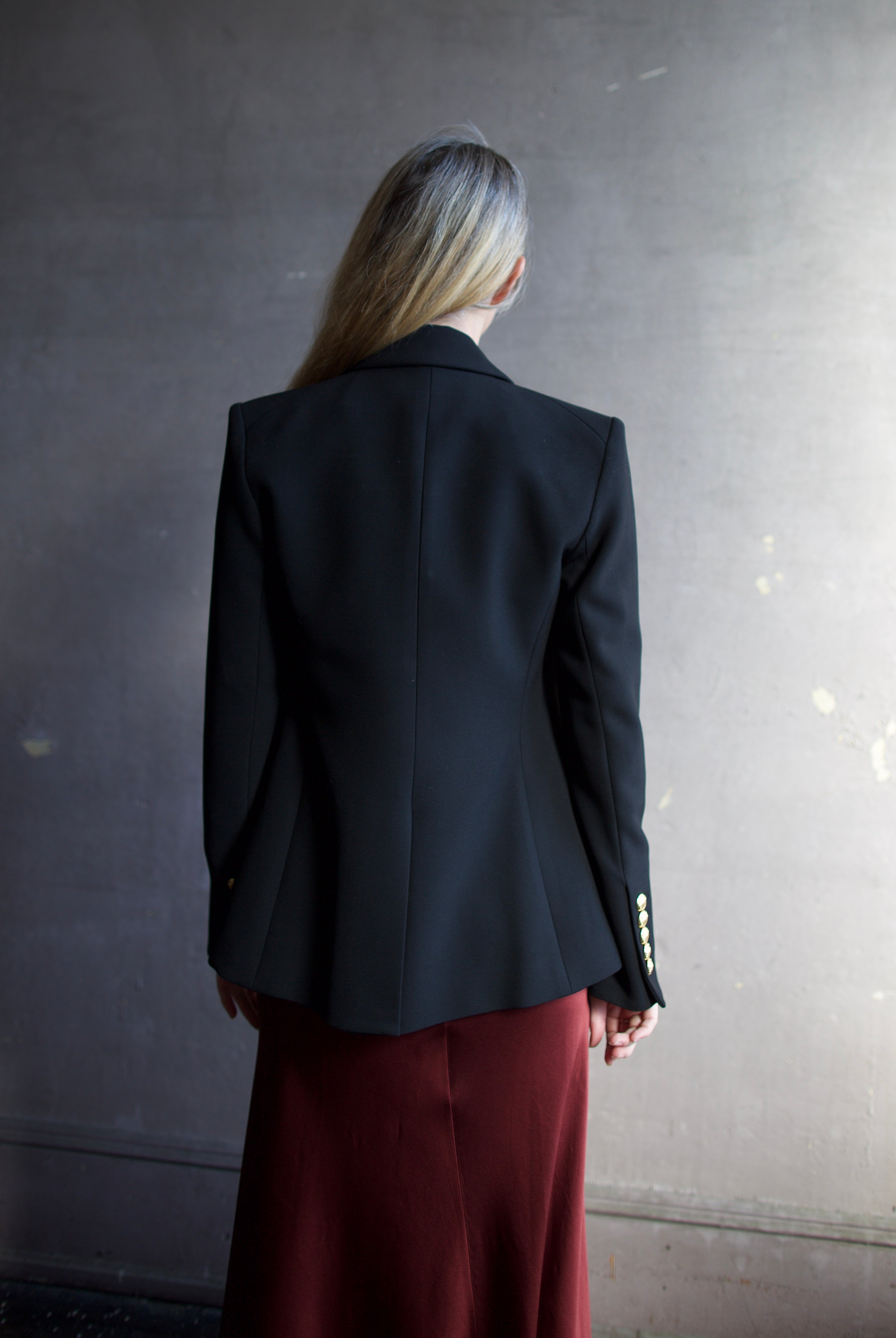 Image featuring a woman wearing the Miller Dickey Jacket by Veronica Beard with a double breasted closure and tailored fit in black with gold color buttons.