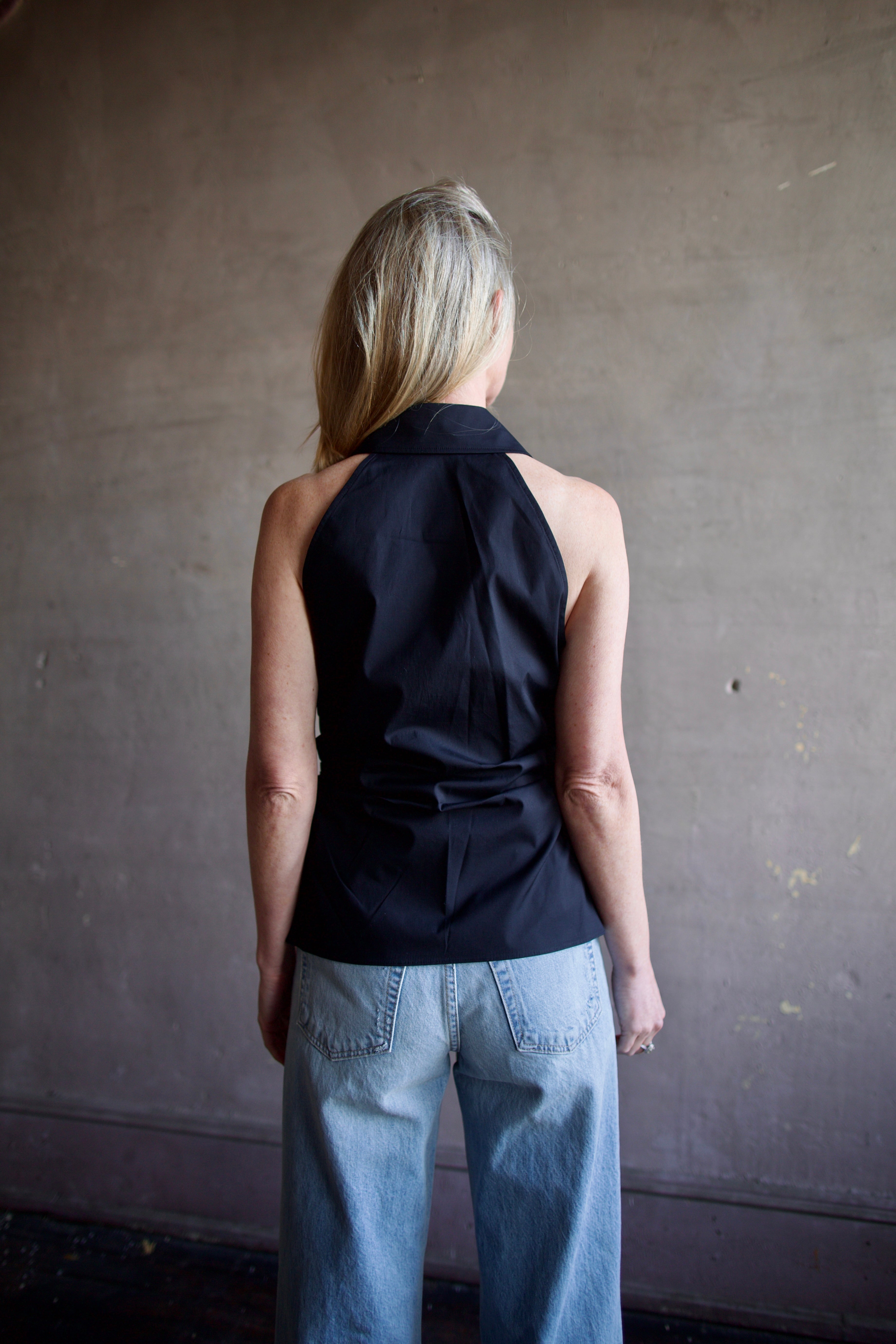 Mature woman wearing luxury women's black cotton blend Veronica Beard Regina Shirt with button front, collar, sleeveless, and tailored fit