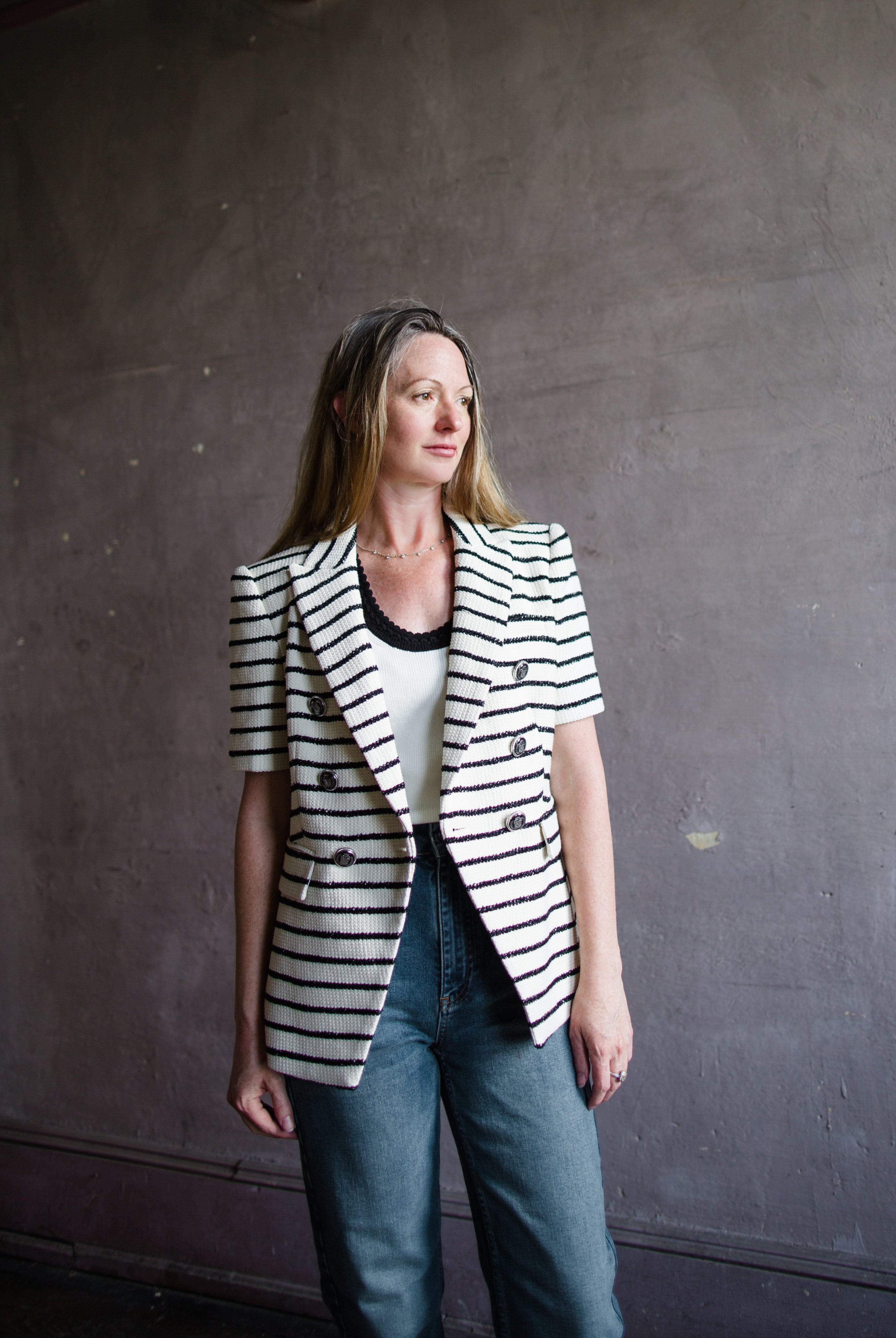 Image featuring a woman wearing the Jenny jacket by Veronica Beard with short sleeves and a tailored fit. The black stripe has a slight metallic sheen on ivory.