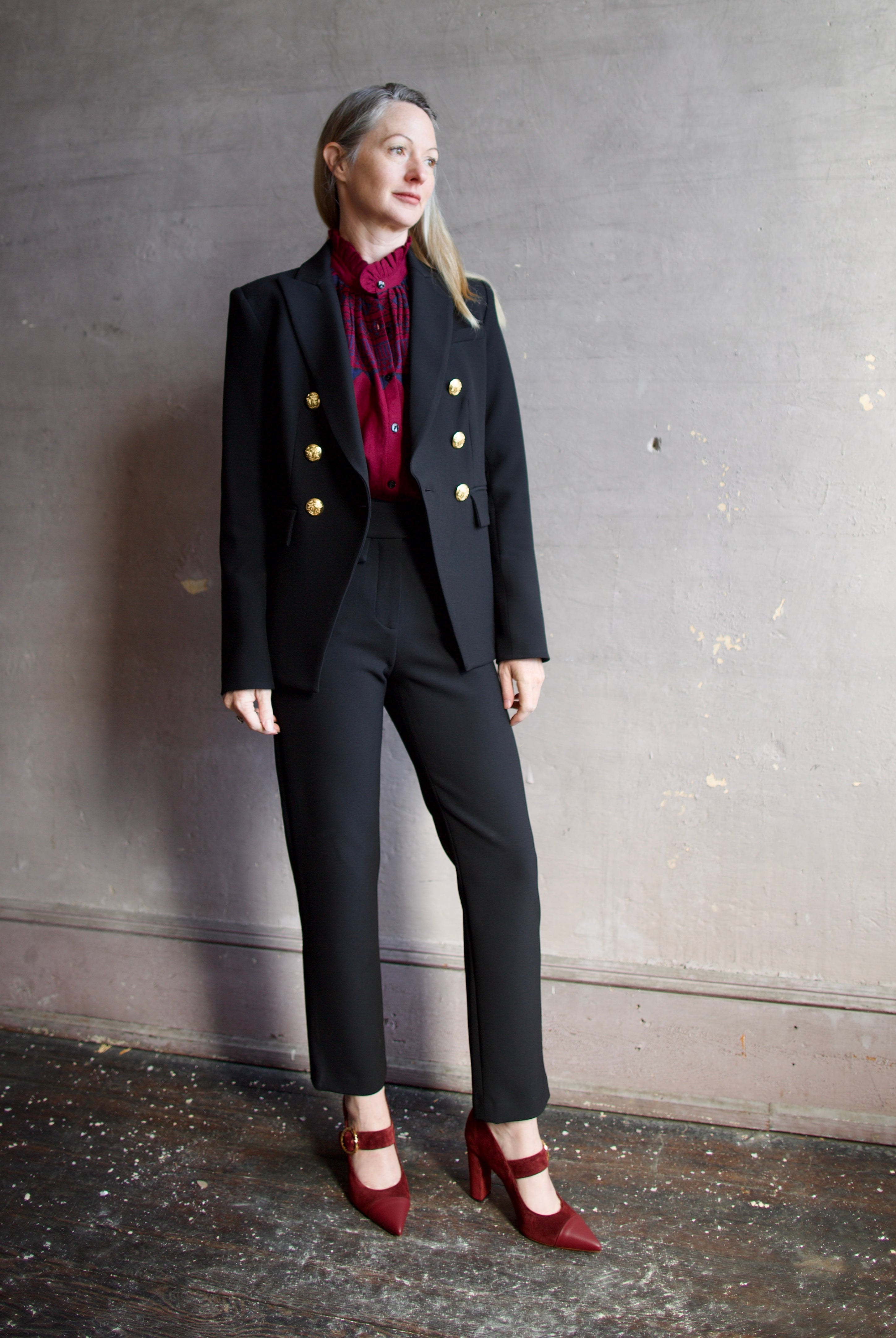 Image featuring a woman wearing the Miller Dickey Jacket by Veronica Beard with a double breasted closure and tailored fit in black with gold color buttons.