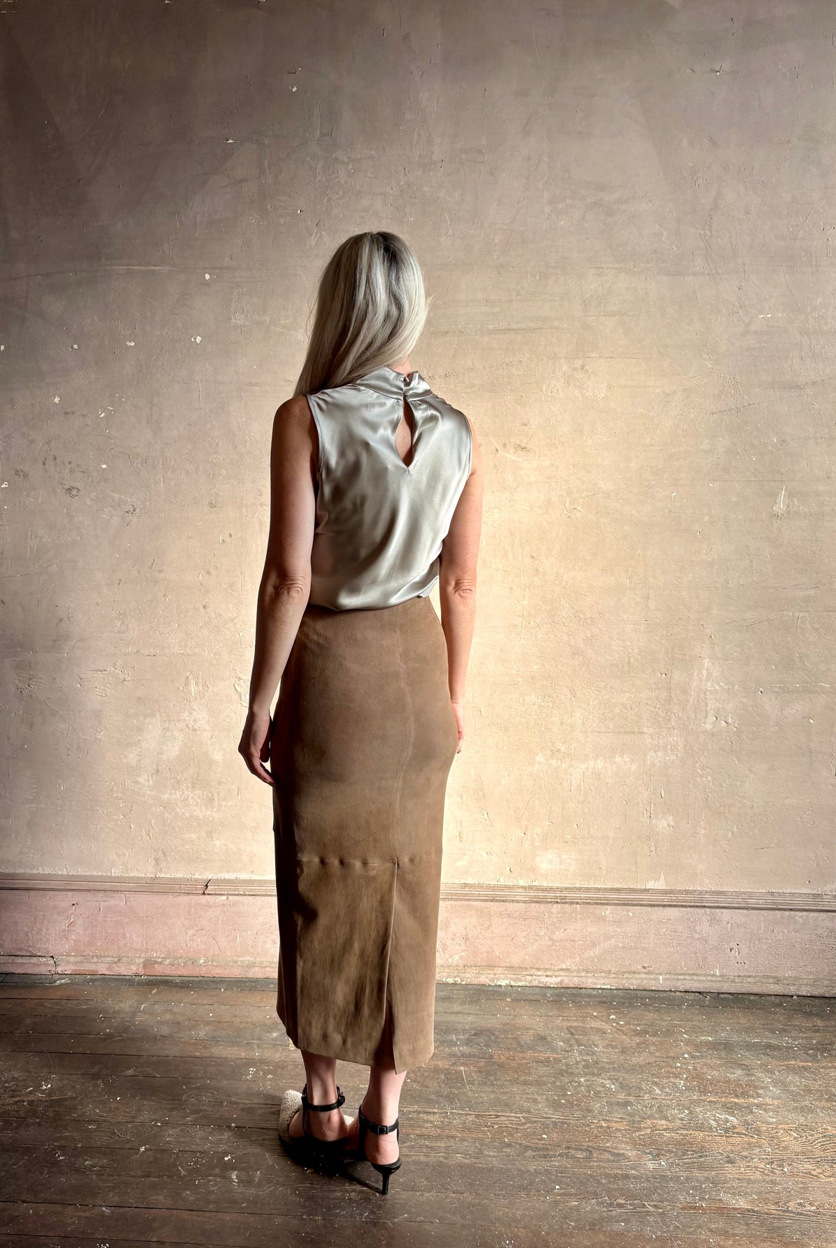 Mature woman wearing Veronica Beard Tam Silk Pewter Top tucked in and styled with a suede leather pencil skirt showing back fluid sihlouette