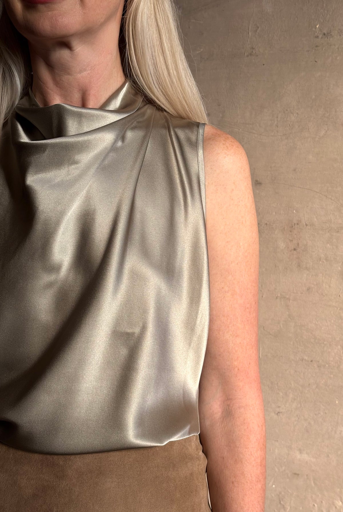 Close-up image showing mature woman wearing a pewter colored Veronica Beard Tam Top with a beautifully draped waterfall neckline there's an intigrated weight to keep draping in place