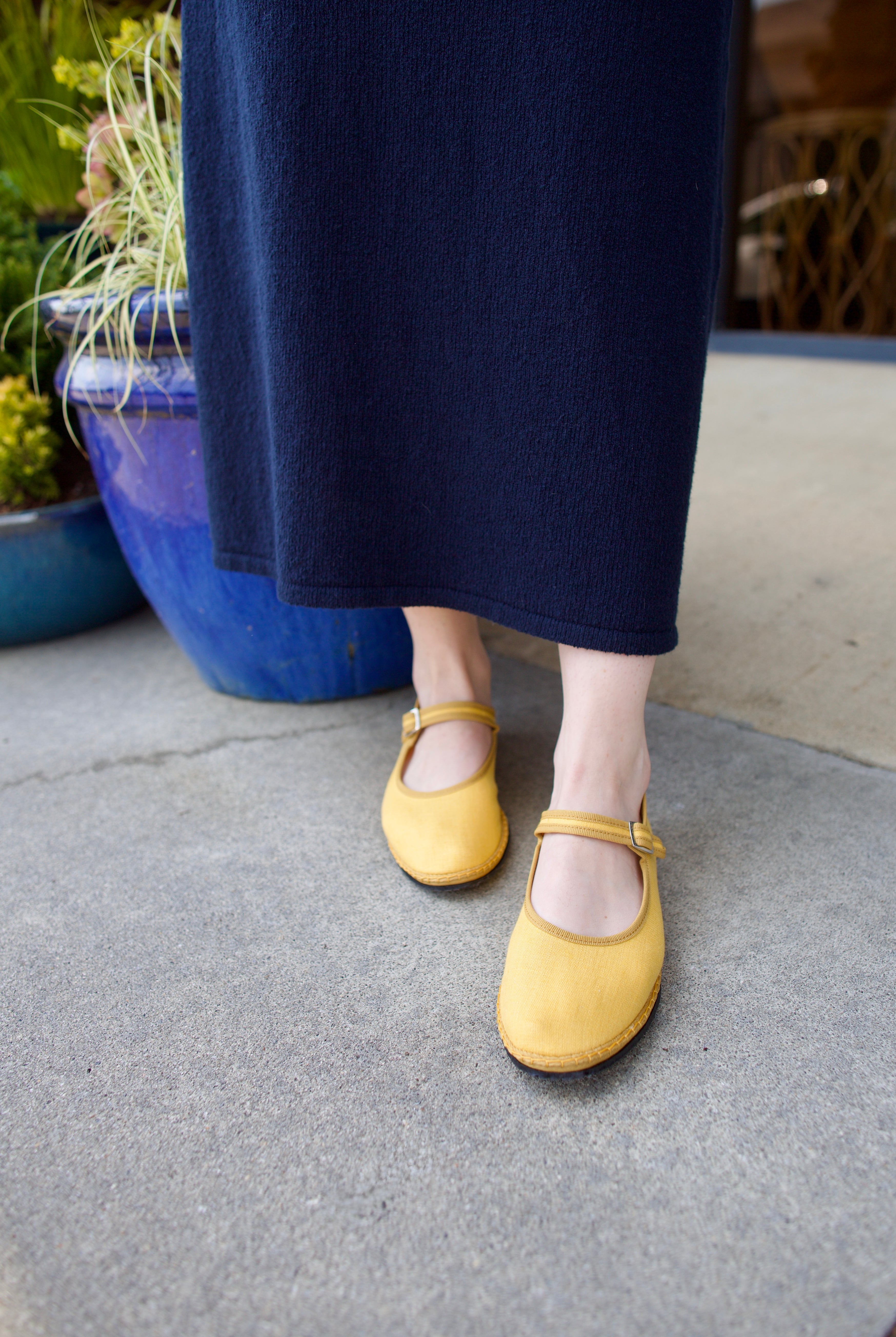 A pair of yellow Vibi Venezia slippers with yellow grosgrain ribbon trim in premium linen construction and traditional Mary Jane design