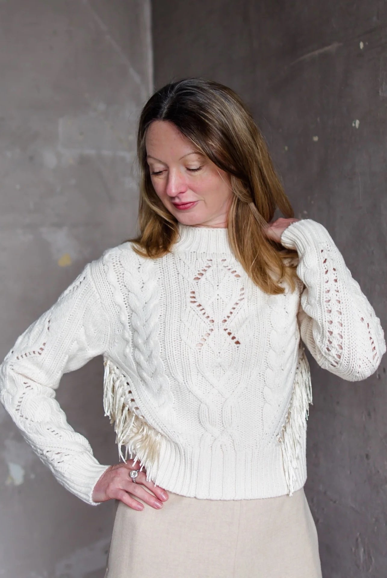 Image featuring a woman wearing the Vince cable-knit sweater is a classic silhouette featuring fringe trim, a crewneck, dropped shoulders, and rib-knit trim.