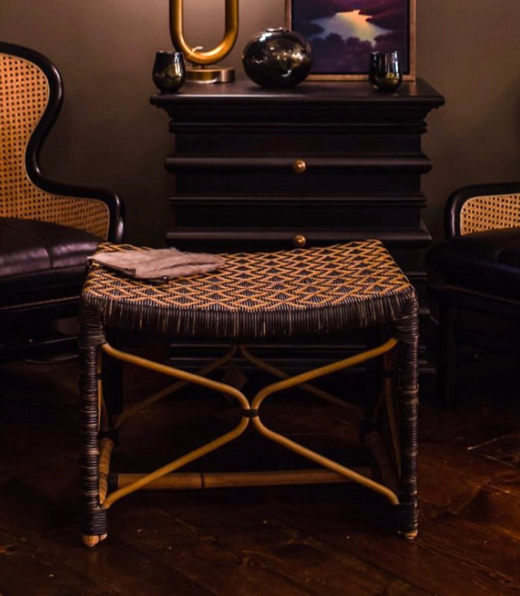 A two-tone rattan stool with a waterfall silhouette design, featuring a diamond pattern, supported by two curved X-shaped stretchers.