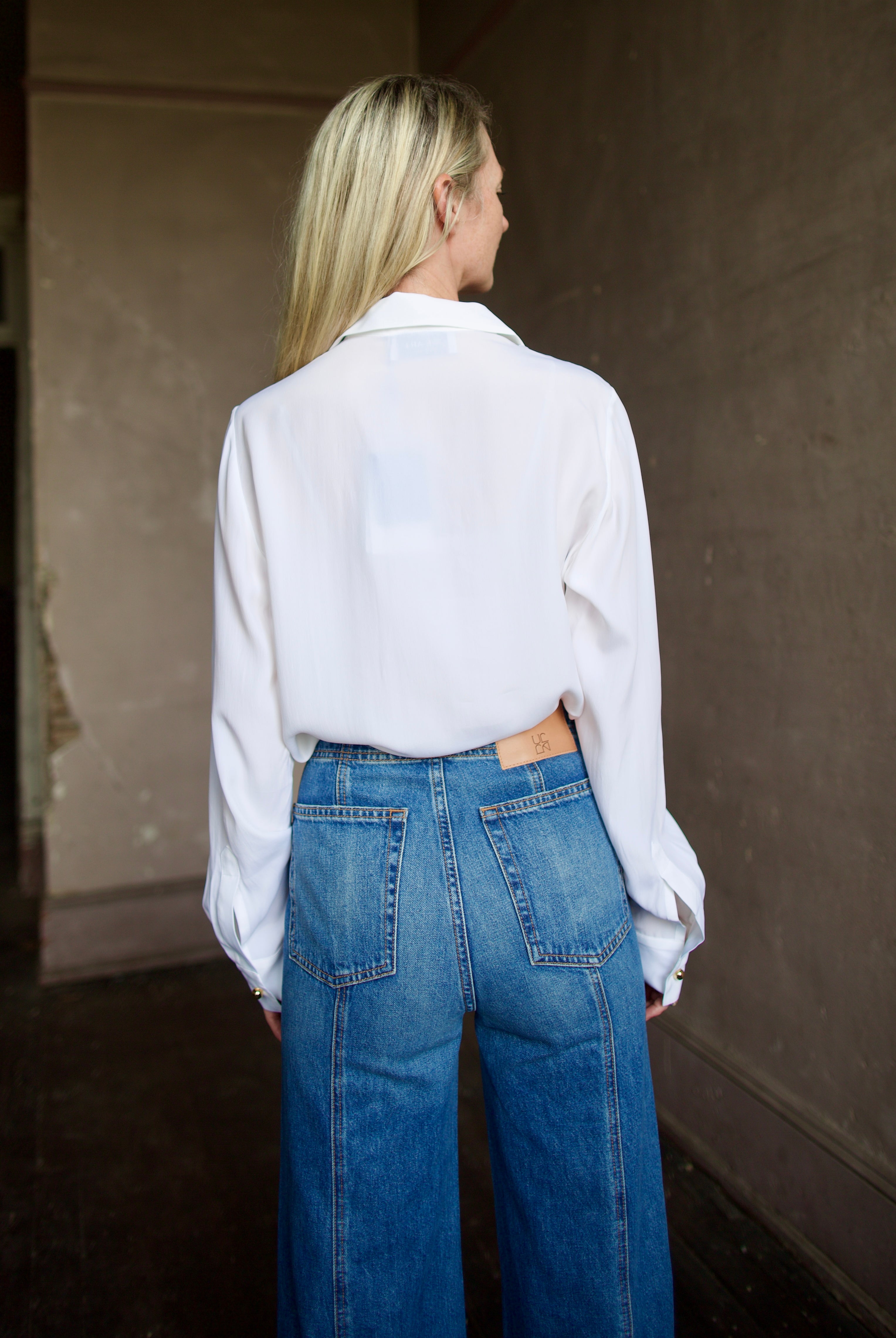 Mature model wearing a white shirt with round gold metal buttons by designer shirt by WE-AR4