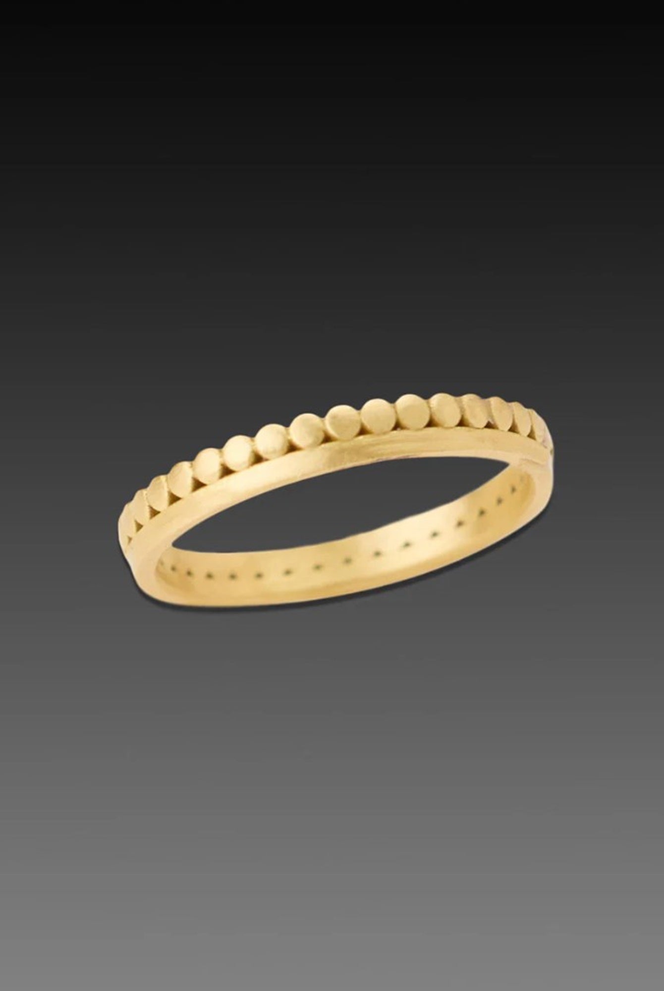 Image of American jeweler Ananda Khalsa hammered 18k matte gold side dot band with continuous side dot band above an elegant gold band