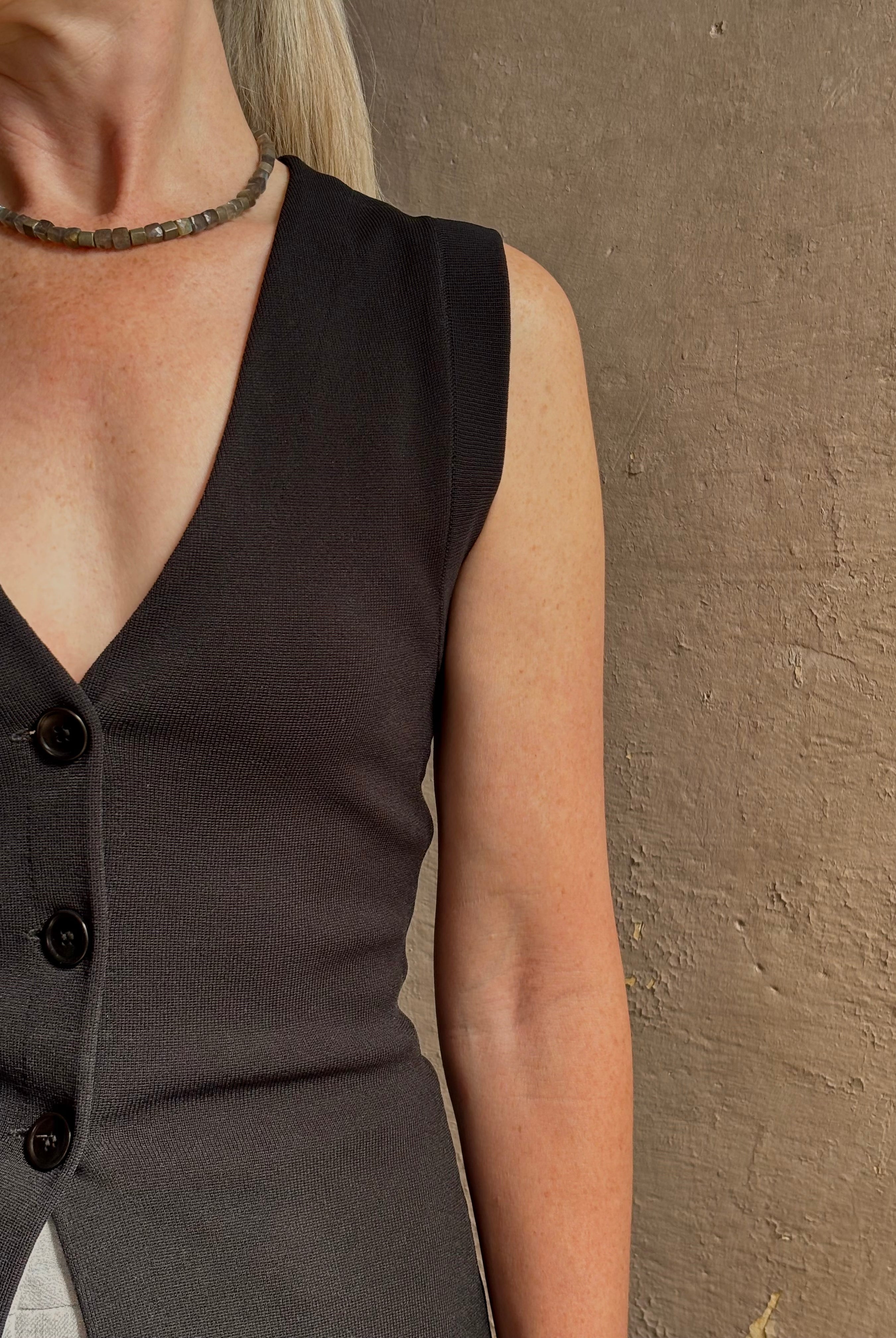 Mature woman wearing a flattering Apiece Apart Marca Knit Top in black with 3 button closure, v- neck and sleeveless