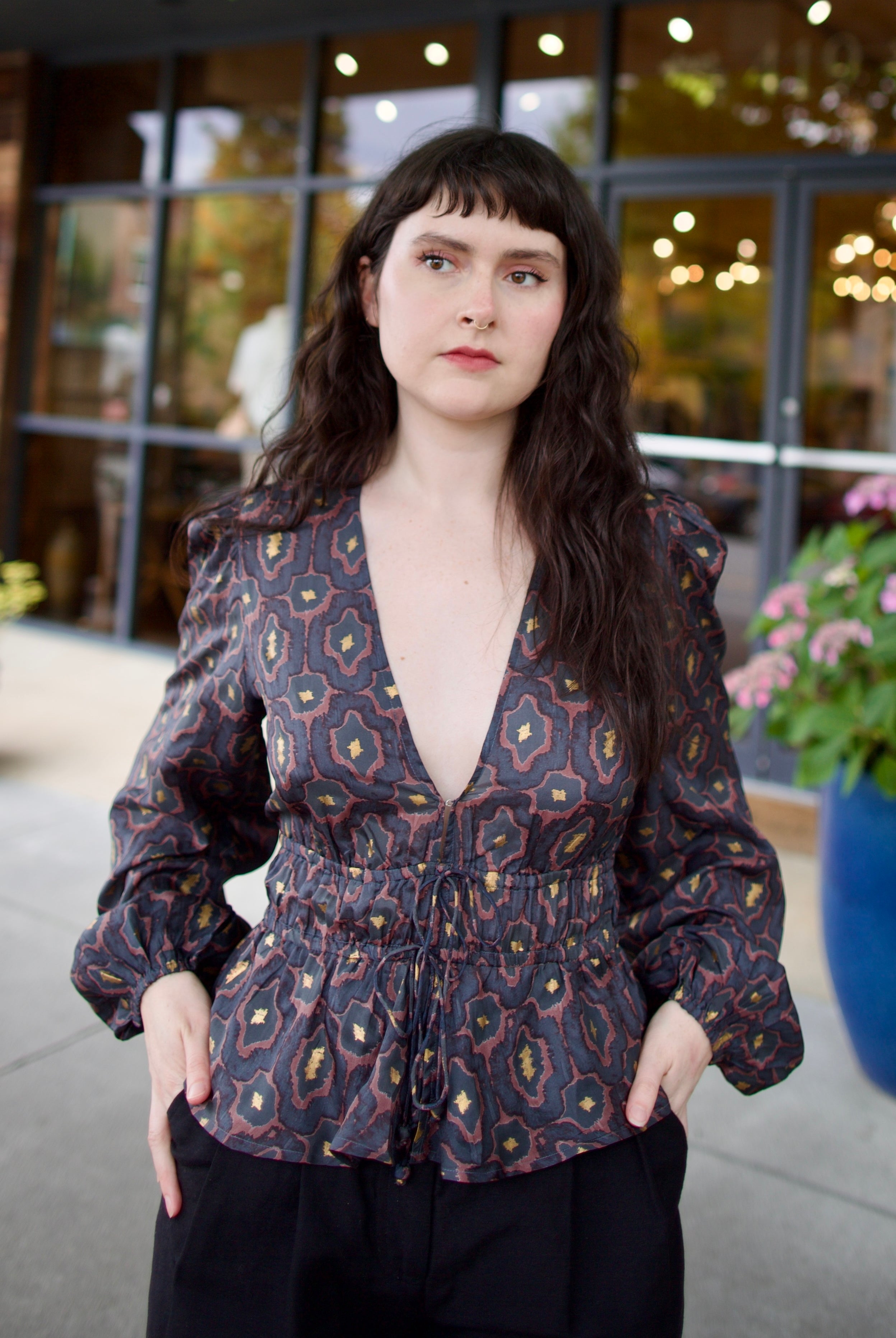 Image of a woman wearing the Hannah Artwear silk Lola Blouse with peplum, long sleeves, v-neck, blockprint and hand applied gold leaf