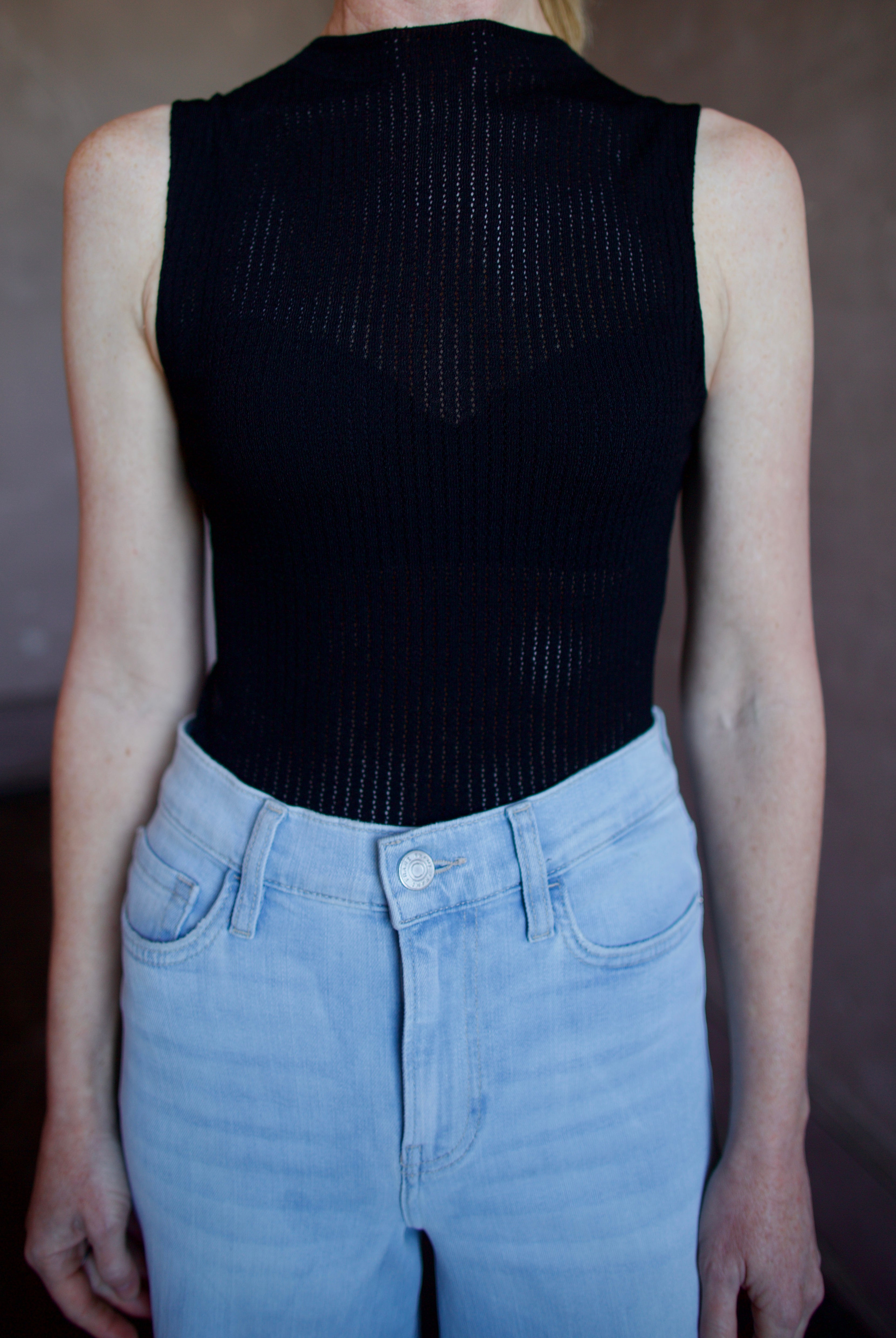 Woman wearing the Rag and Bone Molly Mock Neck black Top in semi-sheer knit construction and expertly designed minimalist silhouette