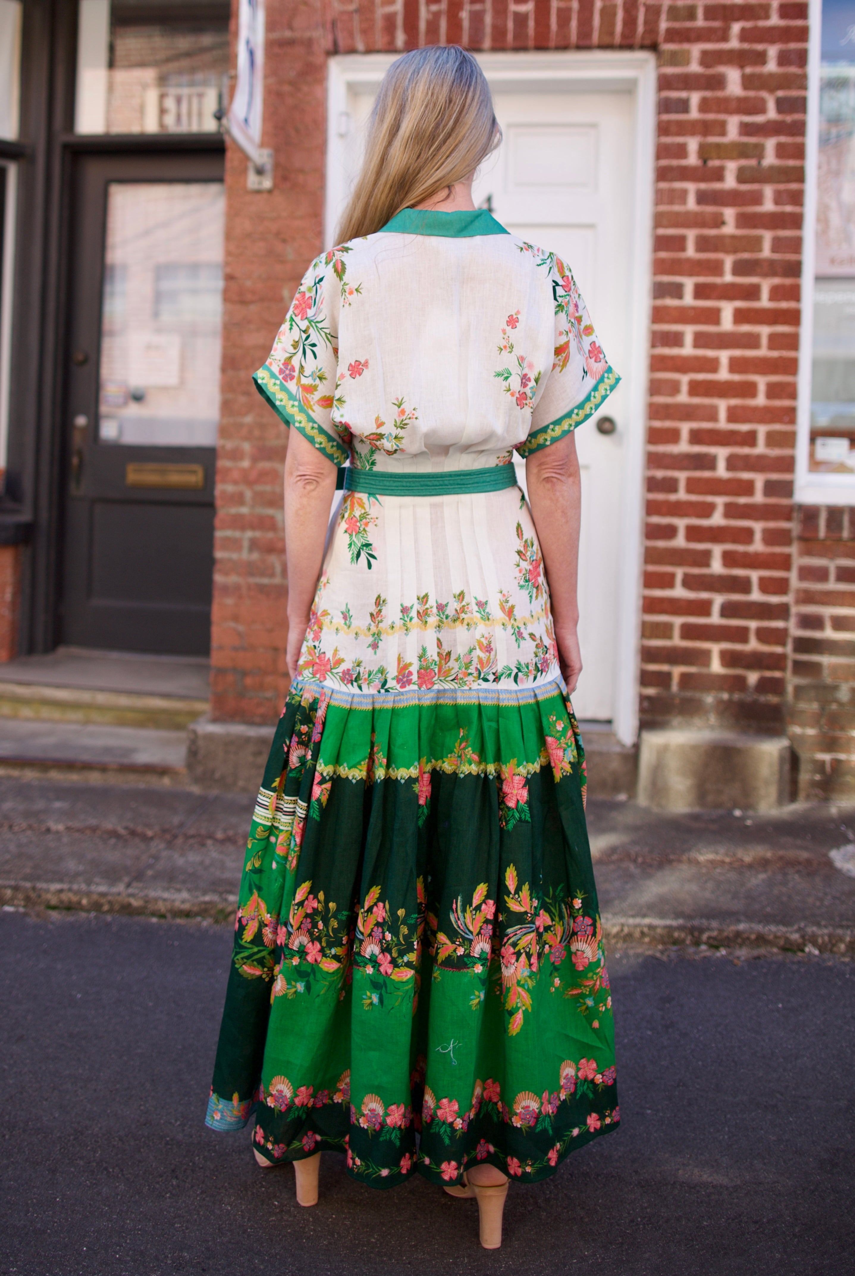 Mature woman wearing luxury women's Saloni Riya B linen dress with button front, rolled short sleeves, removable belt, and drop waist