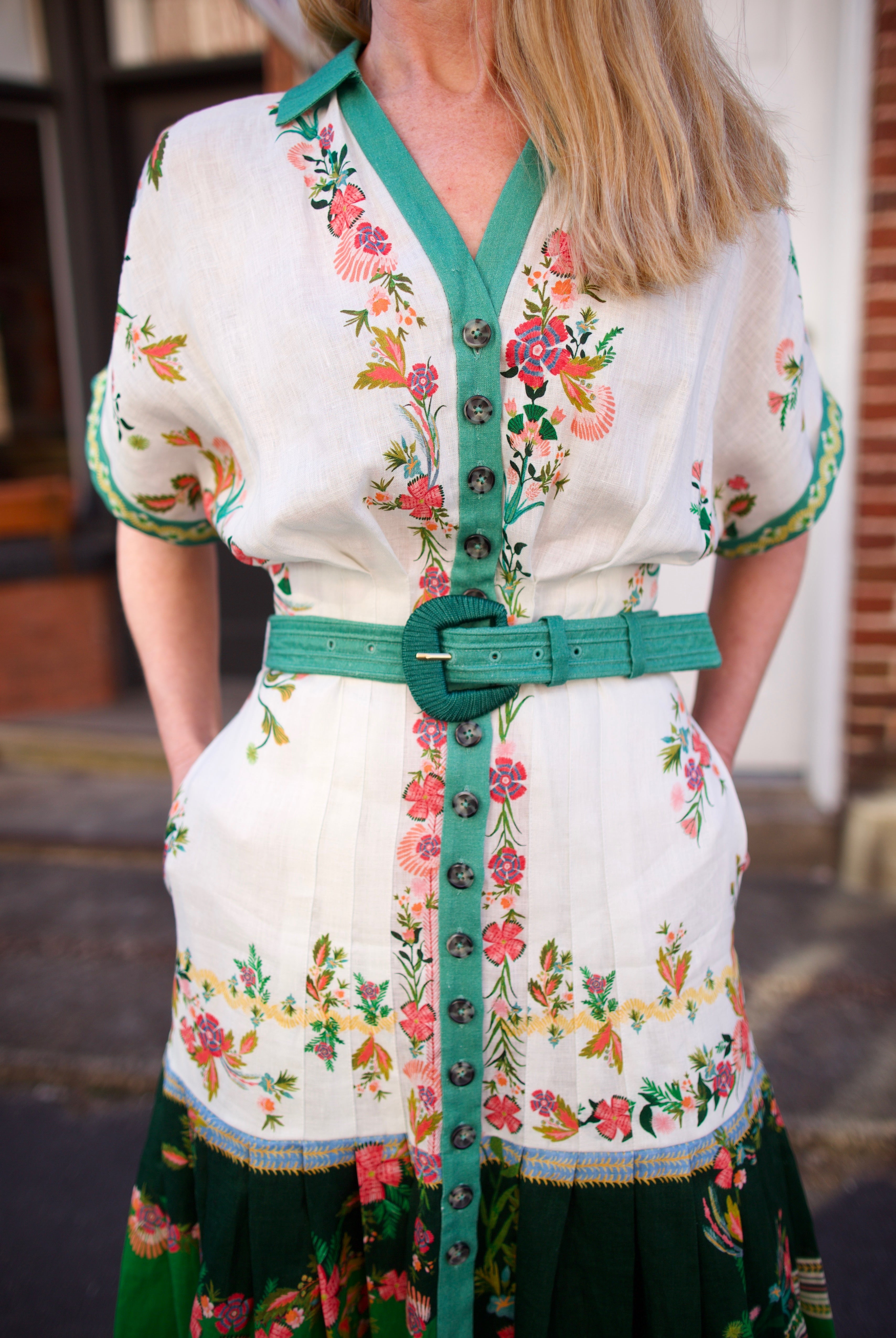 Mature woman wearing luxury women's Saloni Riya B linen dress with button front, rolled short sleeves, removable belt, and drop waist