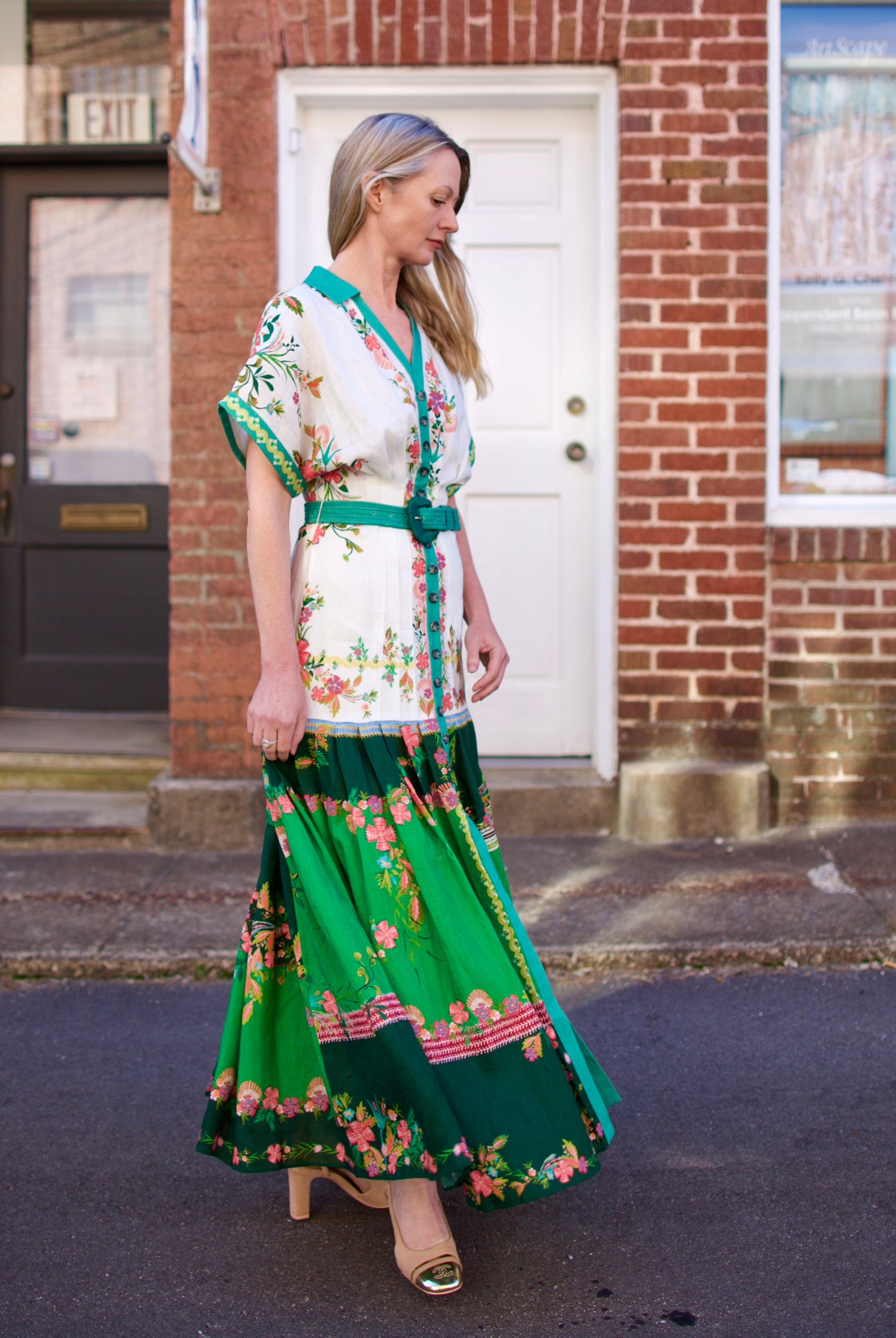 Mature woman wearing luxury women's Saloni Riya B linen dress with button front, rolled short sleeves, removable belt, and drop waist