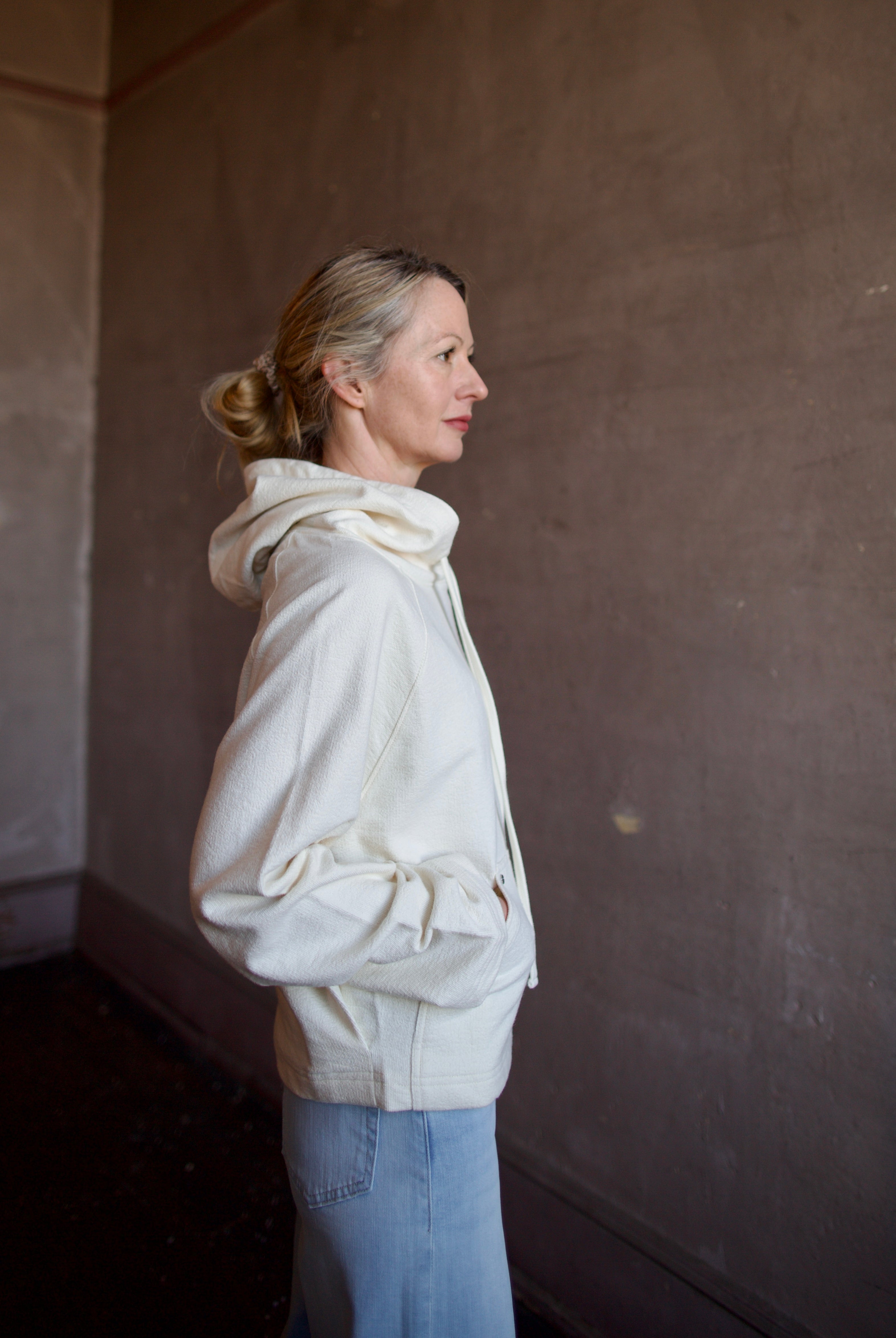 Mature woman wearing luxury TWP Ali's ivory Hoodie featuring raglan sleeves and kangaroo pocket with boxy fit, delivering elevated comfort