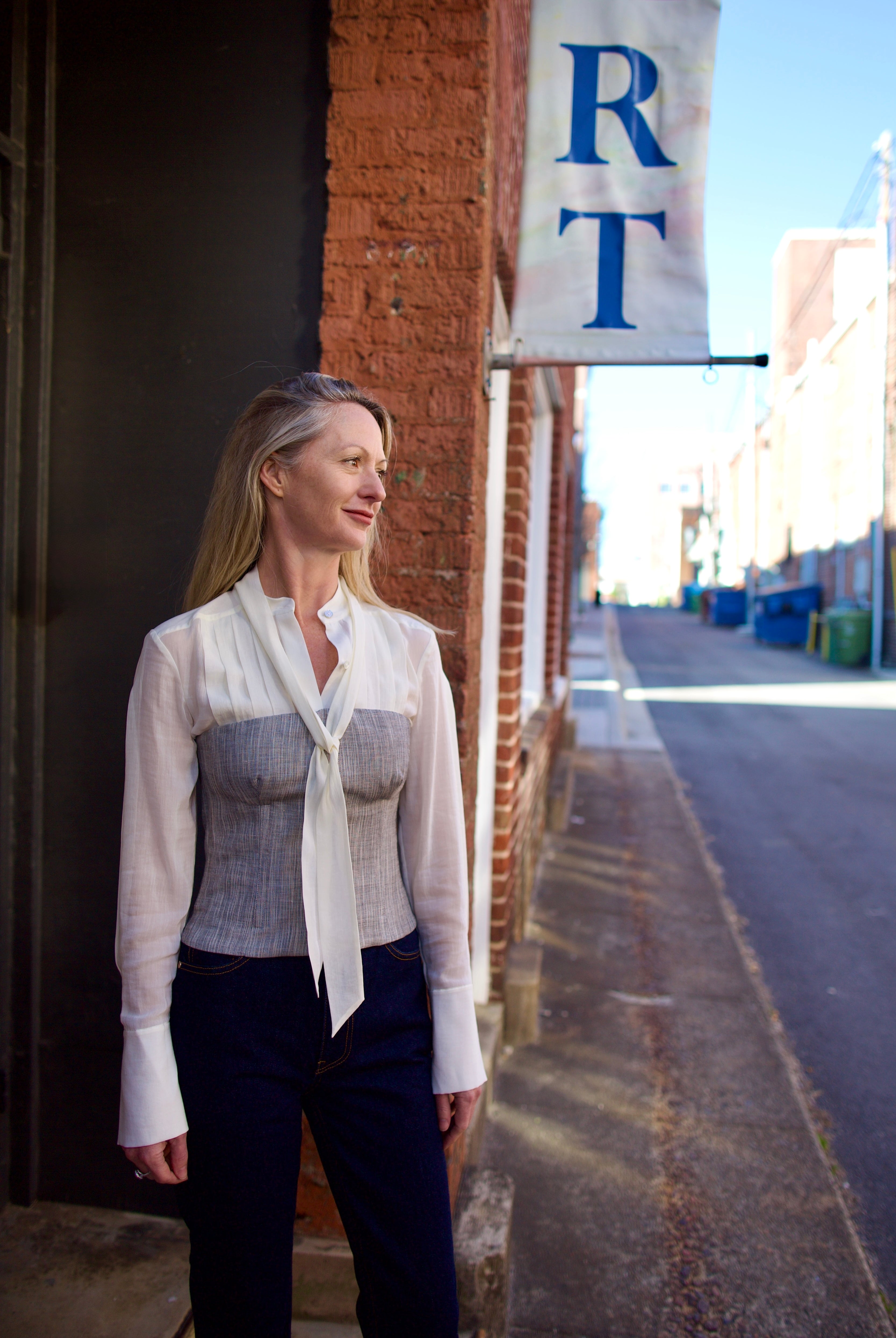 Mature woman wearing luxury brand TWP Jillian cotton-wool bustier in heather grey with bust darts and zip closure perfect for elevated layering