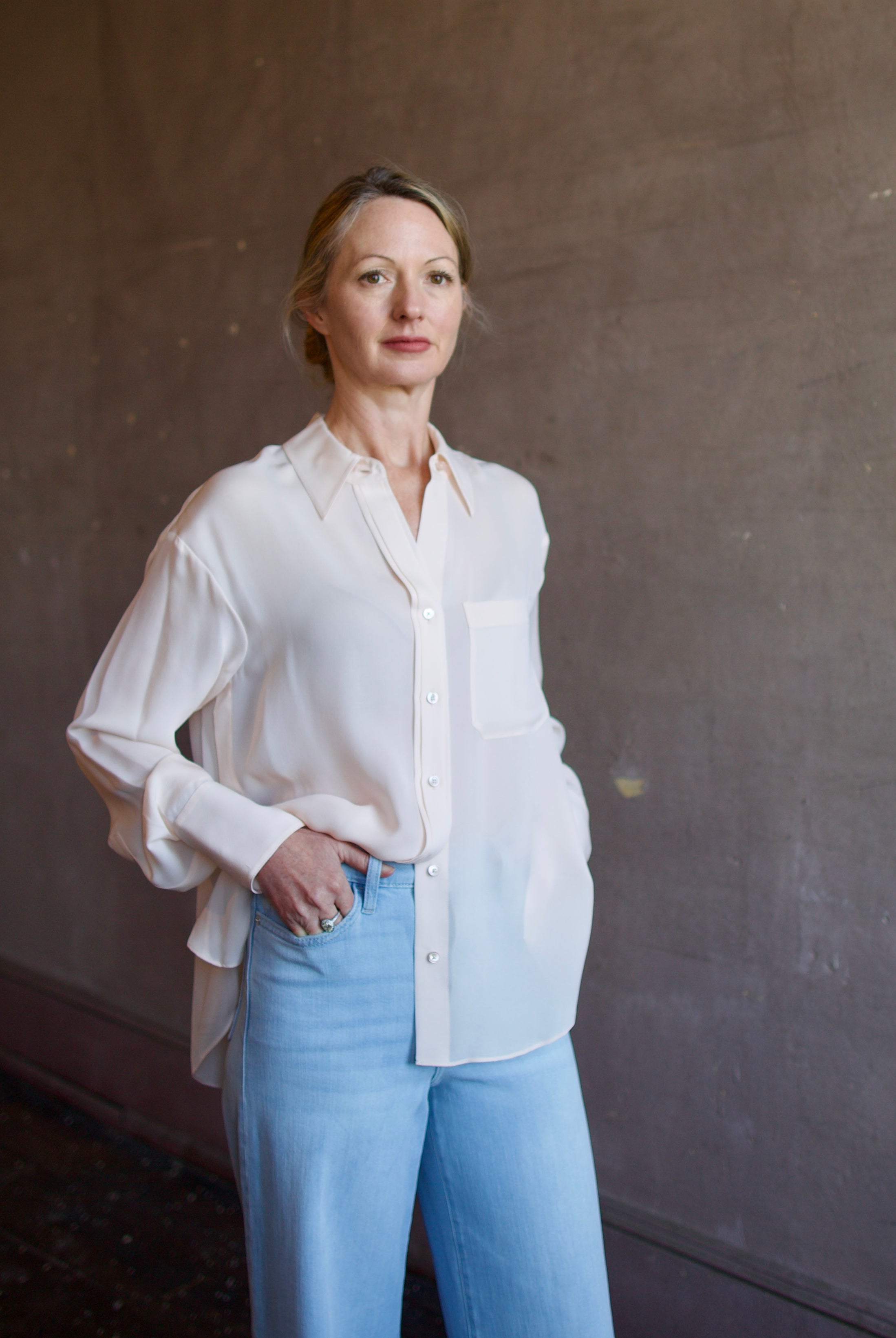 Mature woman wearing luxury women's pink sheer silk Joey blouse by TWP with front pocket, delivering sophisticated elegance