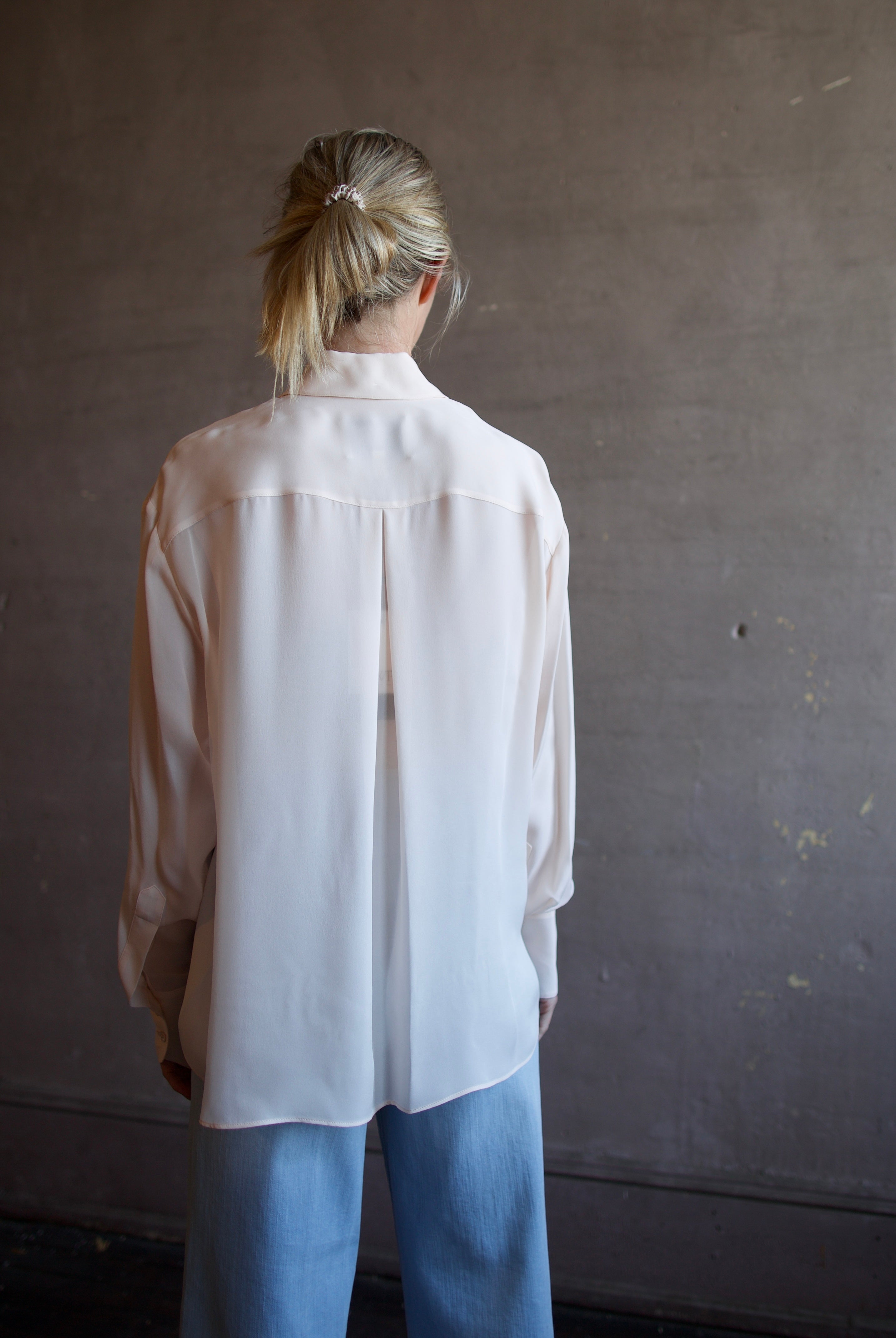 Mature woman wearing luxury women's pink sheer silk Joey blouse by TWP with front pocket, delivering sophisticated elegance