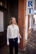 Mature woman wearing elegant luxury women's ivory cotton-silk Patti blouse by TWP with front pleats and buttons  in a slightly cropped fit