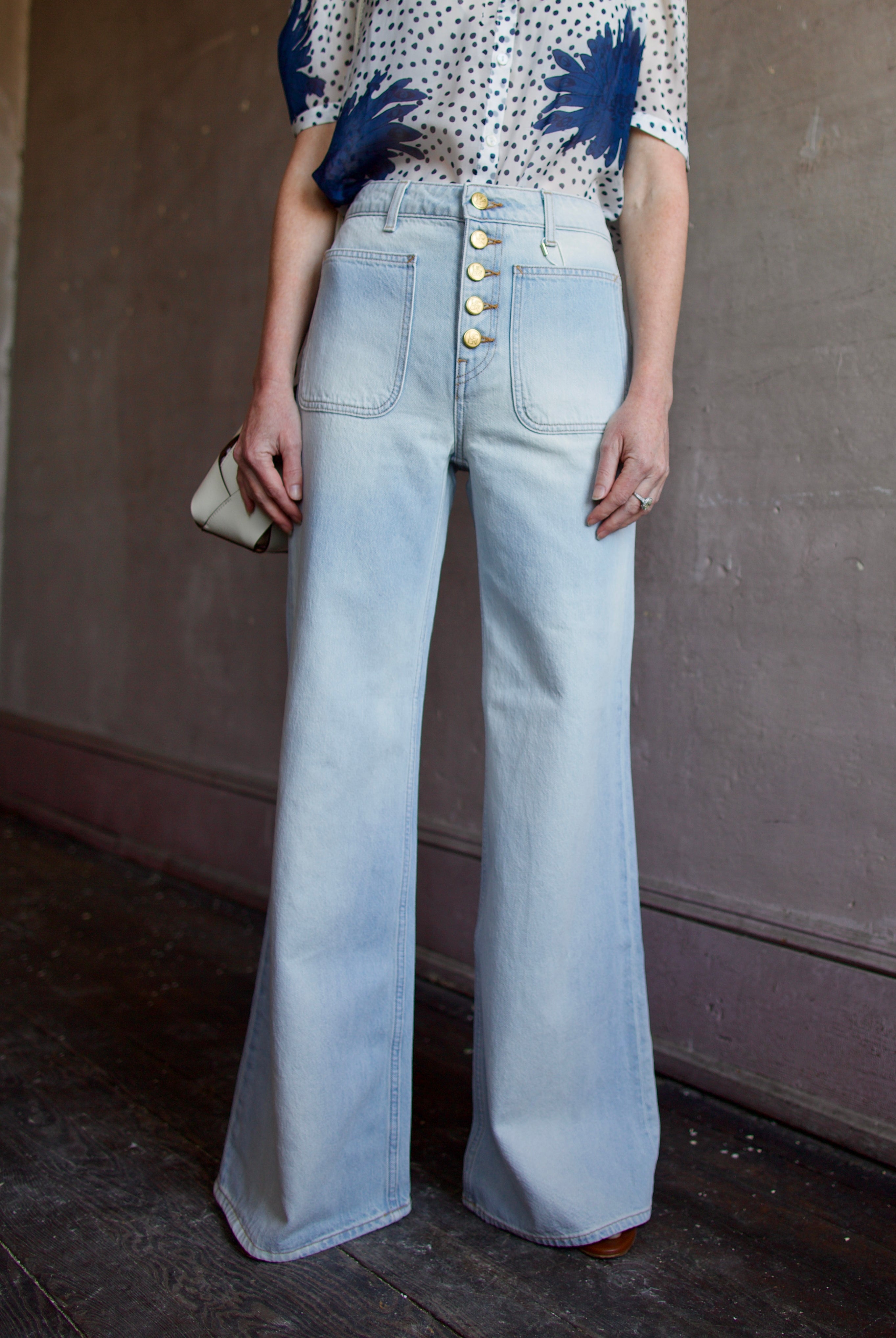 Mature woman wearing Ulla Johnson Gwynne Cielo Jeans in recycled cotton gold button fly light wash front pockets