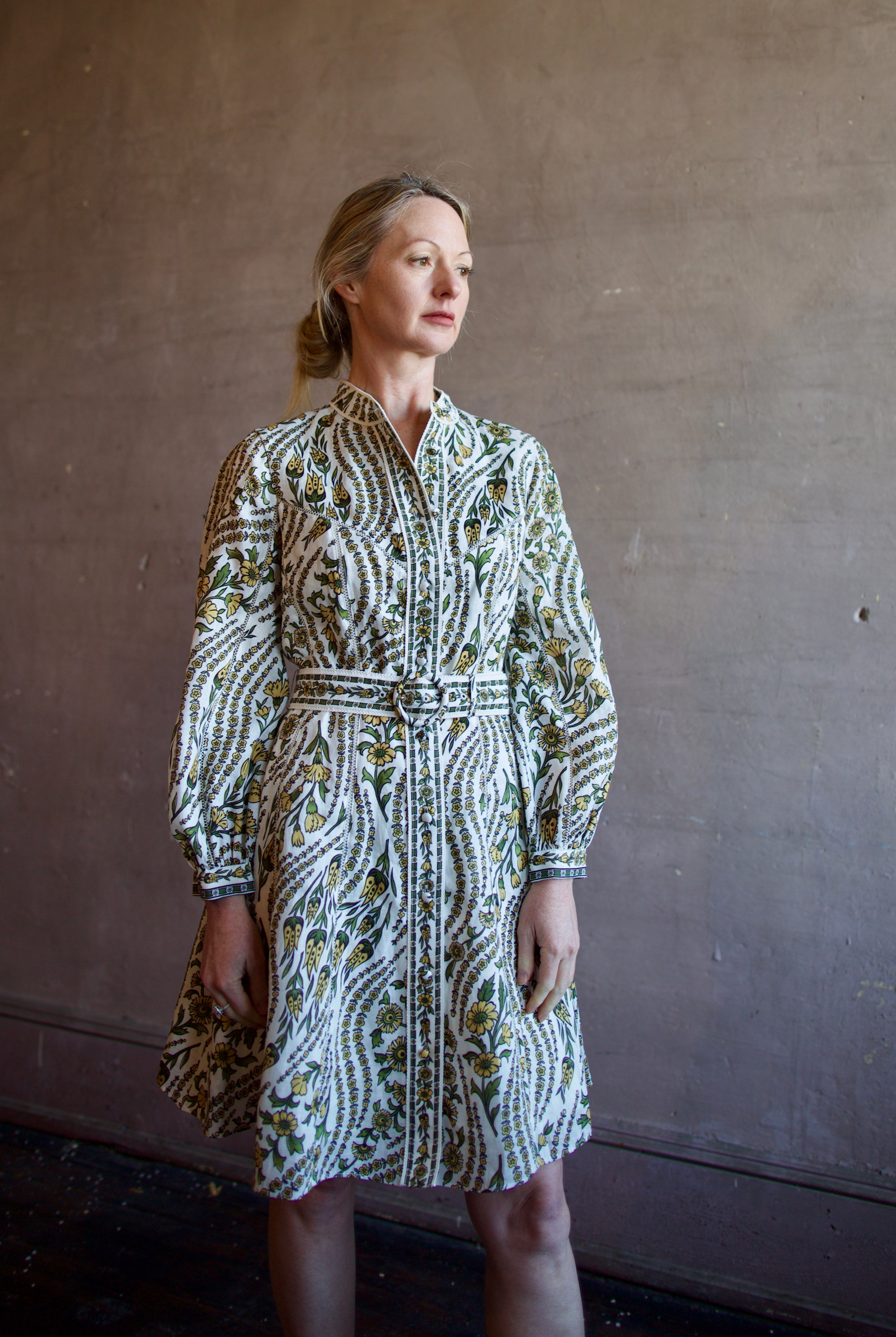 Mature woman wearing luxury women's linen Nolan dress by Veronica Beard featuring button front removable belt long sleeves and knee length skirt