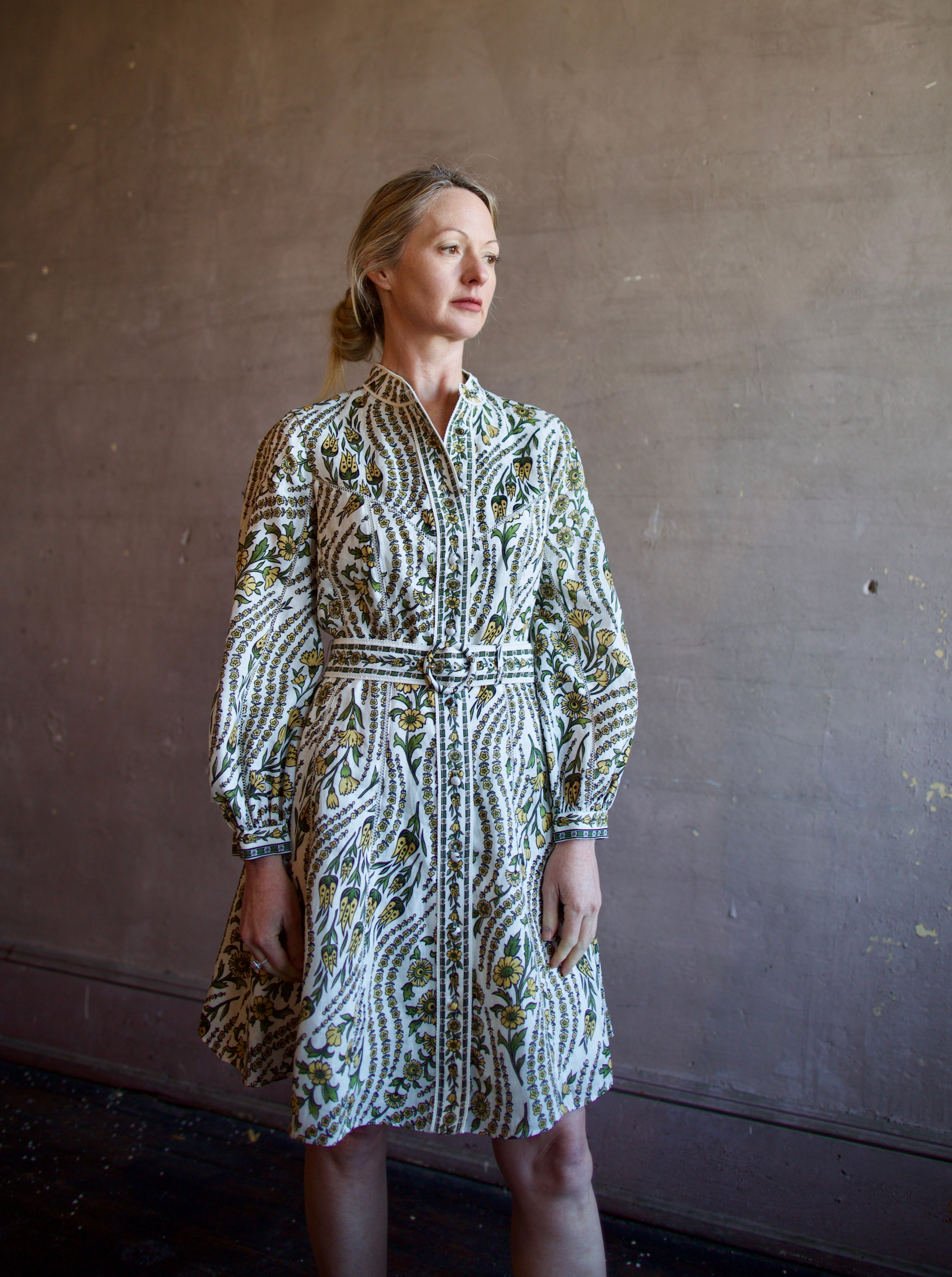 Mature woman wearing luxury women's linen Nolan dress by Veronica Beard featuring button front removable belt long sleeves and knee length skirt