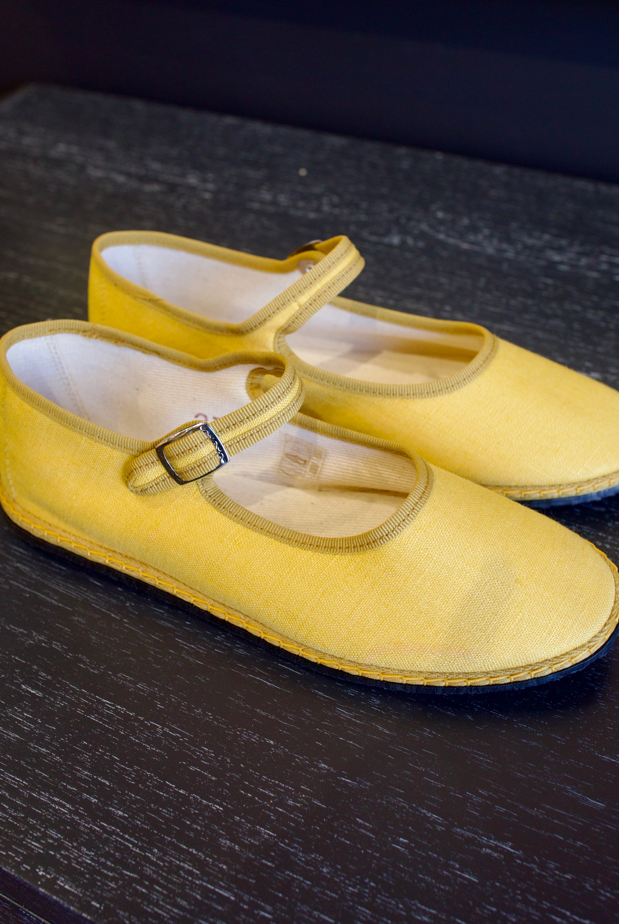 A pair of yellow Vibi Venezia slippers with yellow grosgrain ribbon trim in premium linen construction and traditional Mary Jane design