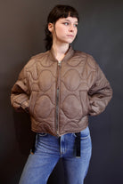 Model wearing Agolde Iona quilted jacket in brown with circular details, side pockets, crew neck, and front zip