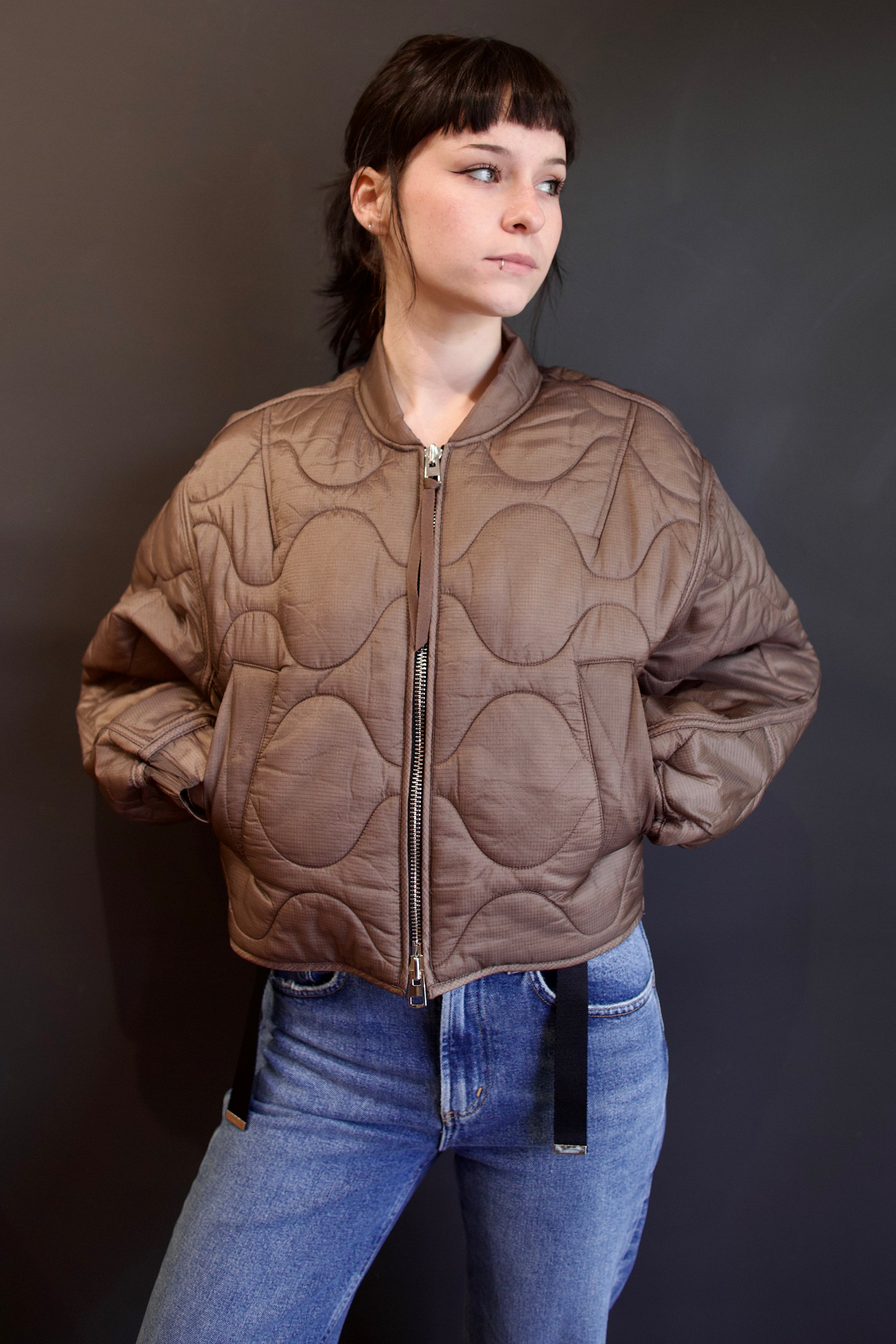 Model wearing Agolde Iona quilted jacket in brown with circular details, side pockets, crew neck, and front zip