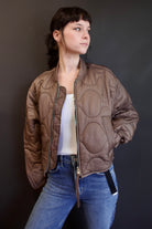 Model wearing Agolde Iona quilted jacket in brown with circular details, side pockets, crew neck, and front zip