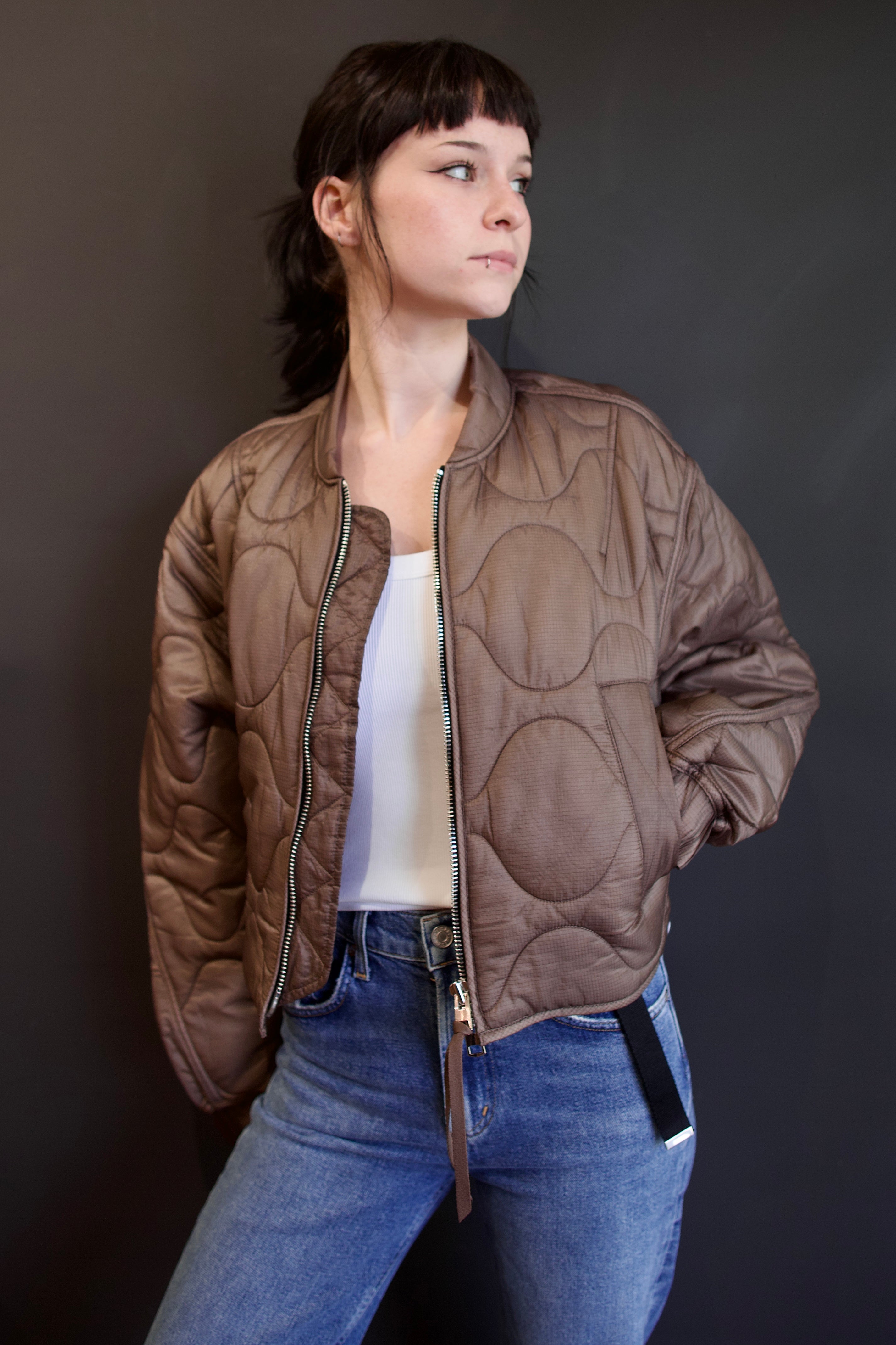 Model wearing Agolde Iona quilted jacket in brown with circular details, side pockets, crew neck, and front zip
